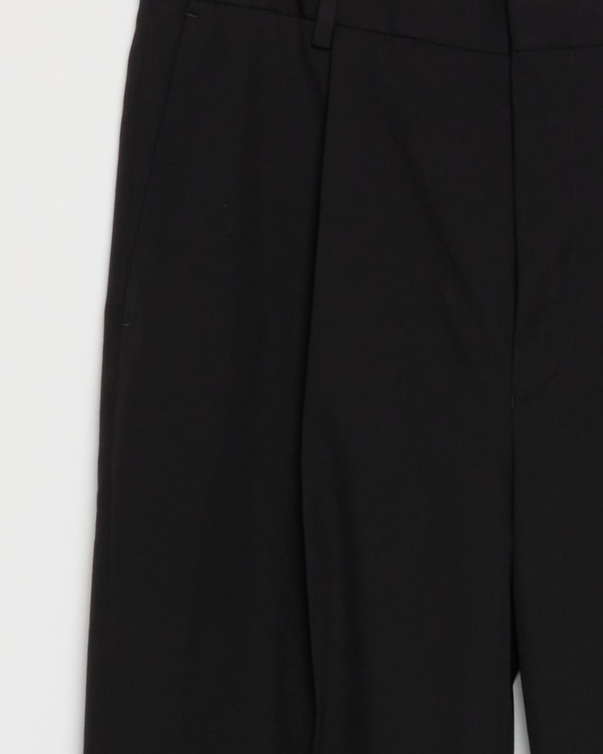 Black dress pants from the Dries Van Noten Cotton-Wool Suit in Black are shown against a white background, highlighting the upper half with waistband, belt loops, and front pleats. These tailored trousers exemplify the refined elegance and modern craftsmanship synonymous with Dries Van Noten, offering a timeless silhouette without visible buttons or zipper.