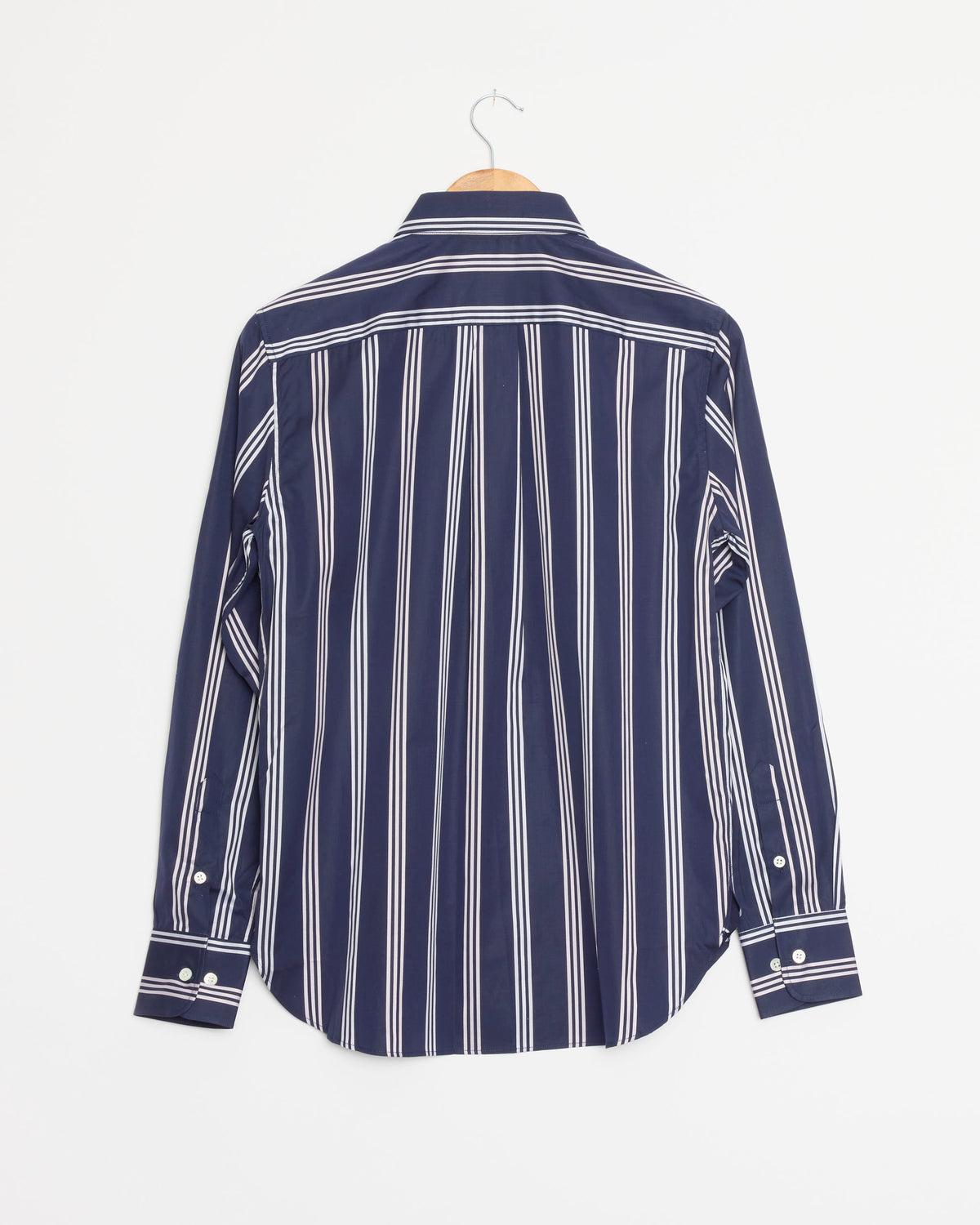 The Hommegirls Original Shirt in Navy Canopy, a long-sleeve classic style crafted from 100% cotton and featuring vertical white stripes, is displayed from the back on a wooden hanger against a plain white background.