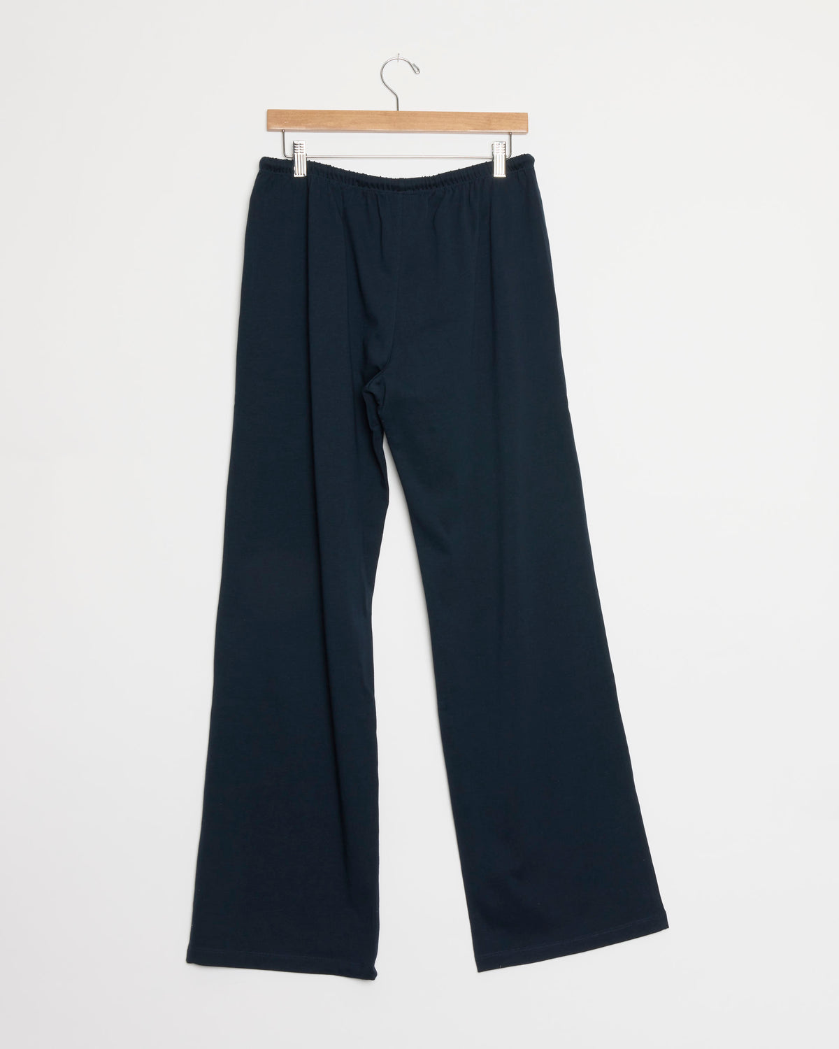 Lounge Pant in Dark Navy by Hommegirls, featuring a wide-leg silhouette and an elastic waistband, crafted from 100% cotton, displayed on a wooden hanger against a plain white background.