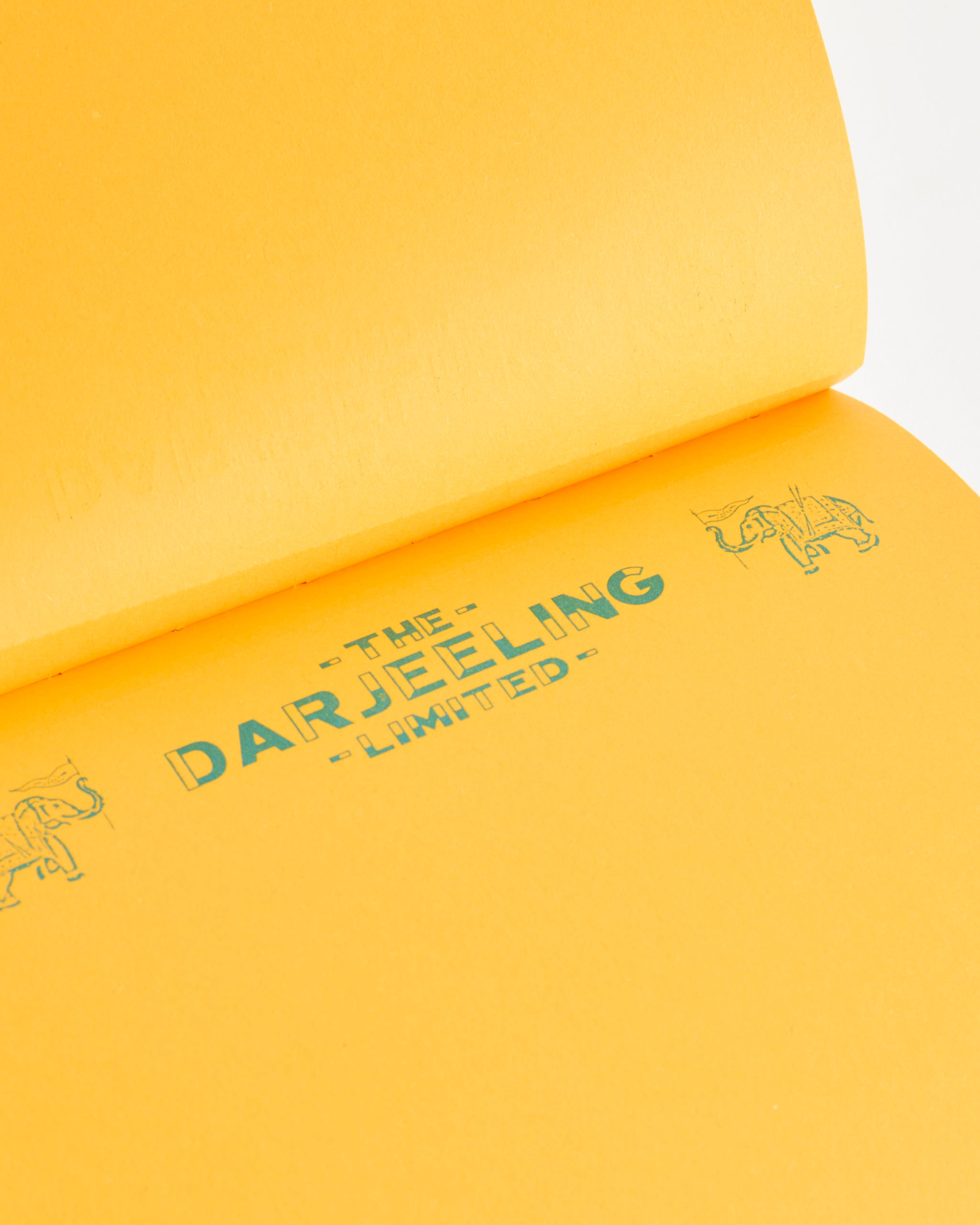 Astier de Villatte’s Wes Anderson Letter Paper Notepad features a yellow page with The Darjeeling Limited in green and tiny elephants—a vintage-inspired design reminiscent of classic Wes Anderson stationery.