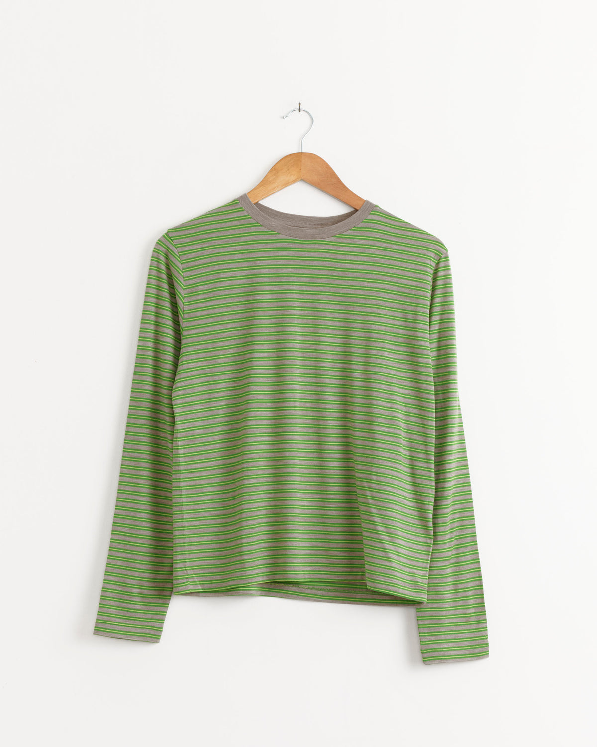 Soft Wool Jersey Long Sleeve Tee in Green Stripe by Auralee, featuring horizontal green and gray stripes, hanging on a wooden hanger.