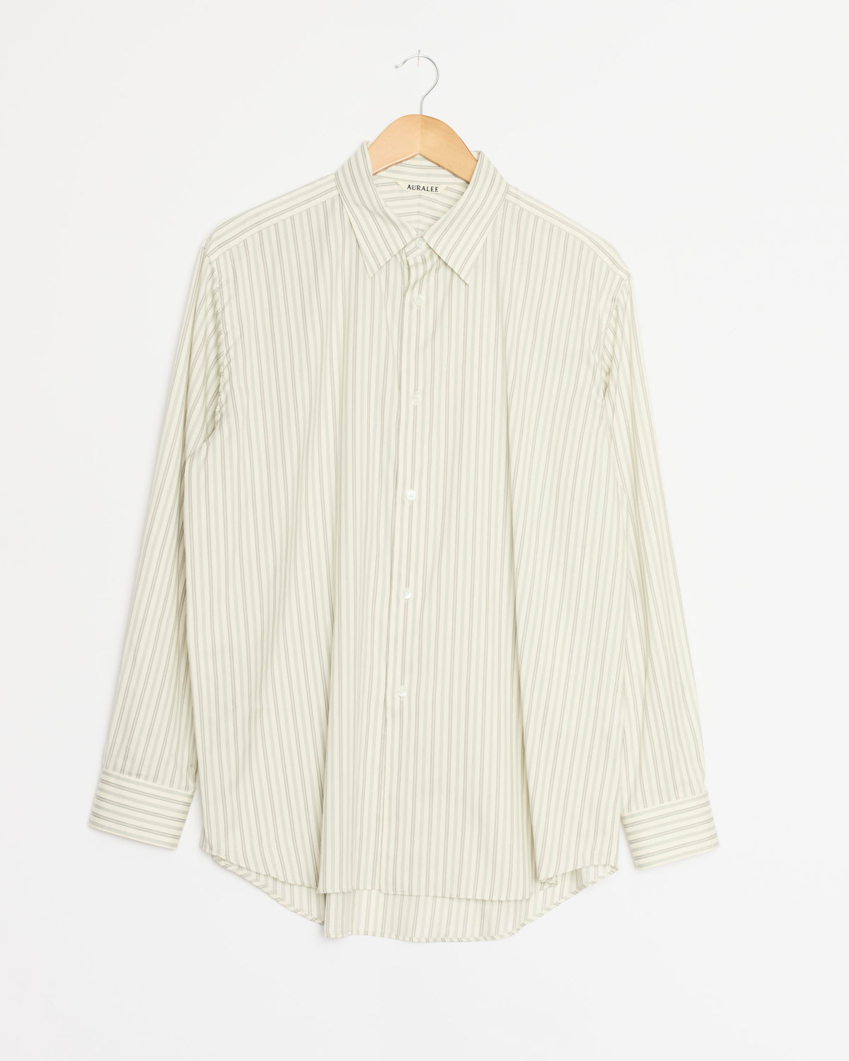 An Auralee Cotton Silk Stripe Shirt in Light Grey, featuring long sleeves and thin vertical white stripes, expertly crafted from luxurious Egyptian Giza cotton, displayed on a wooden hanger against a plain white background.
