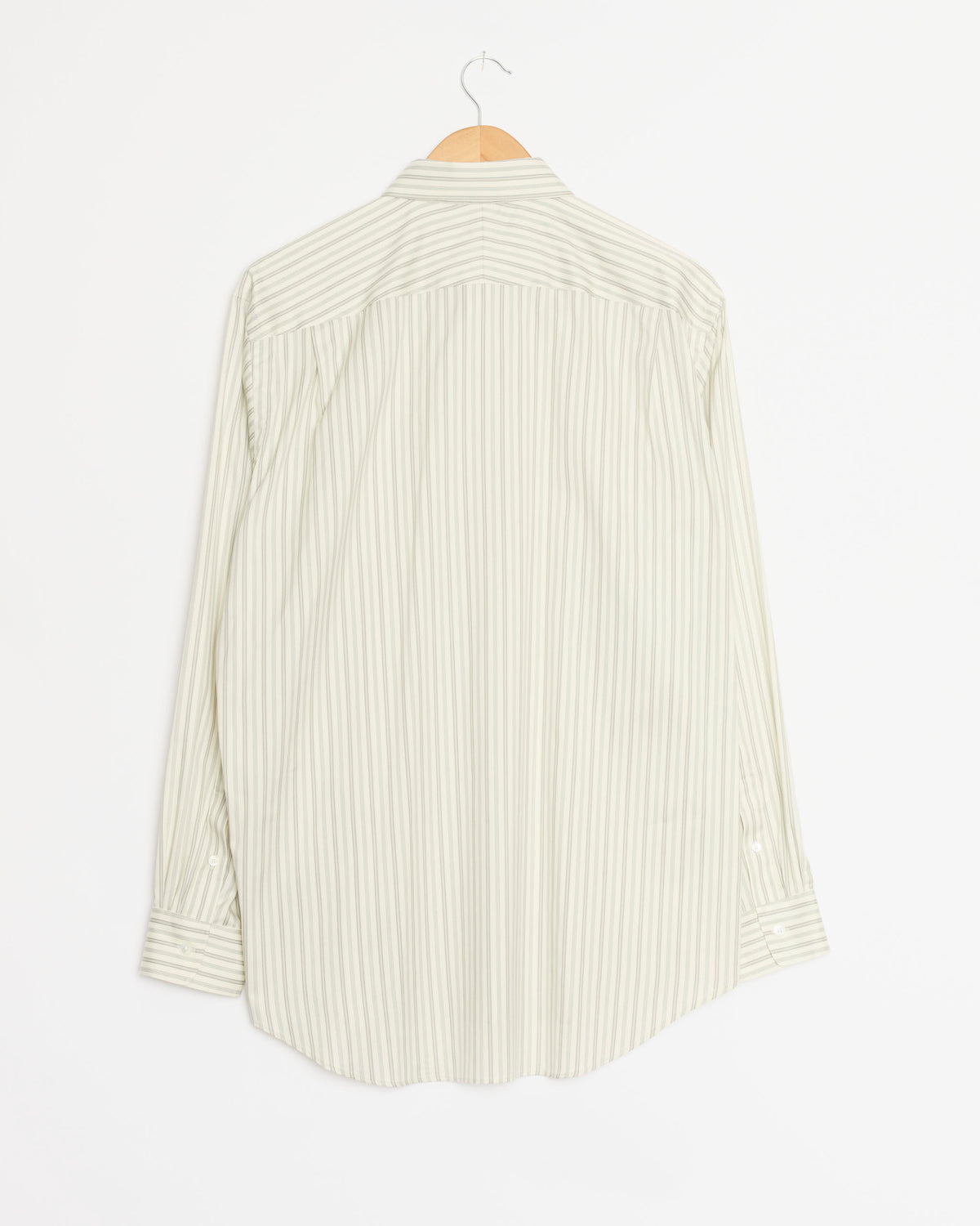 A light-grey, long-sleeve Cotton Silk Stripe Shirt by Auralee, featuring thin vertical stripes, hangs on a wooden hanger against a white background with the back facing forward. Expertly crafted in Japan from premium Egyptian Giza cotton and silk, this shirt showcases Auralee’s refined style and exceptional craftsmanship.