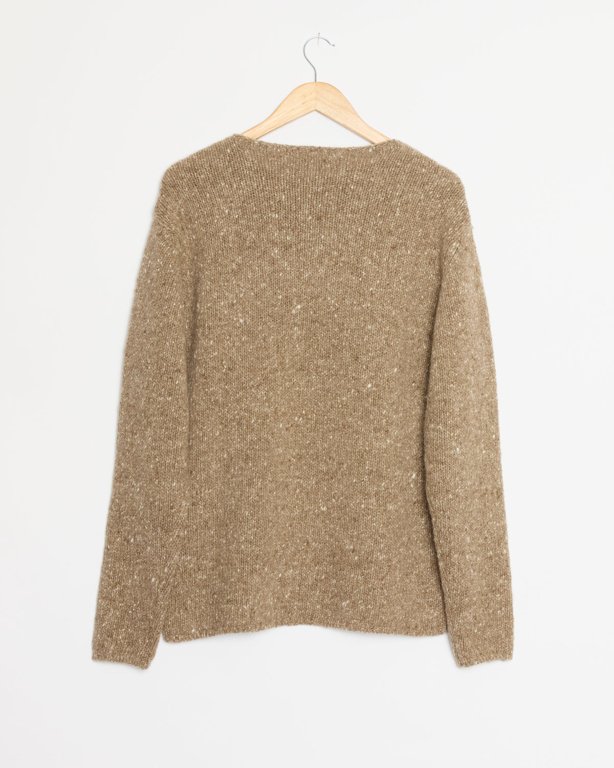 A Low Gauge Homespun Tweed Knit Pullover in Top Brown by Auralee, featuring long sleeves and a cozy knit texture, hangs on a wooden hanger against a plain white background, displayed from the back.