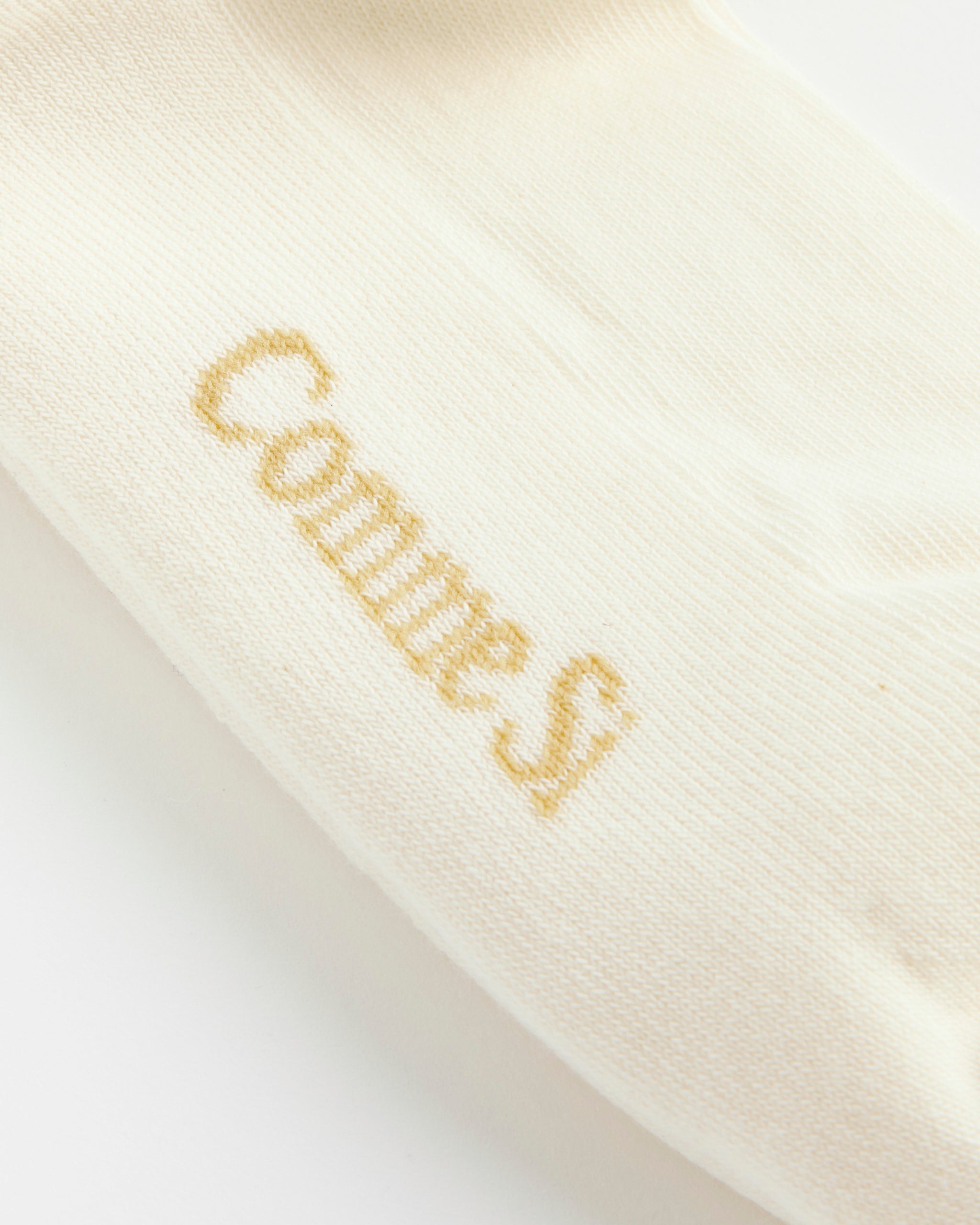 Close-up of a Striped Tube Sock in Burgundy/Capri by Comme Si, featuring the brand's name embroidered on the fabric.