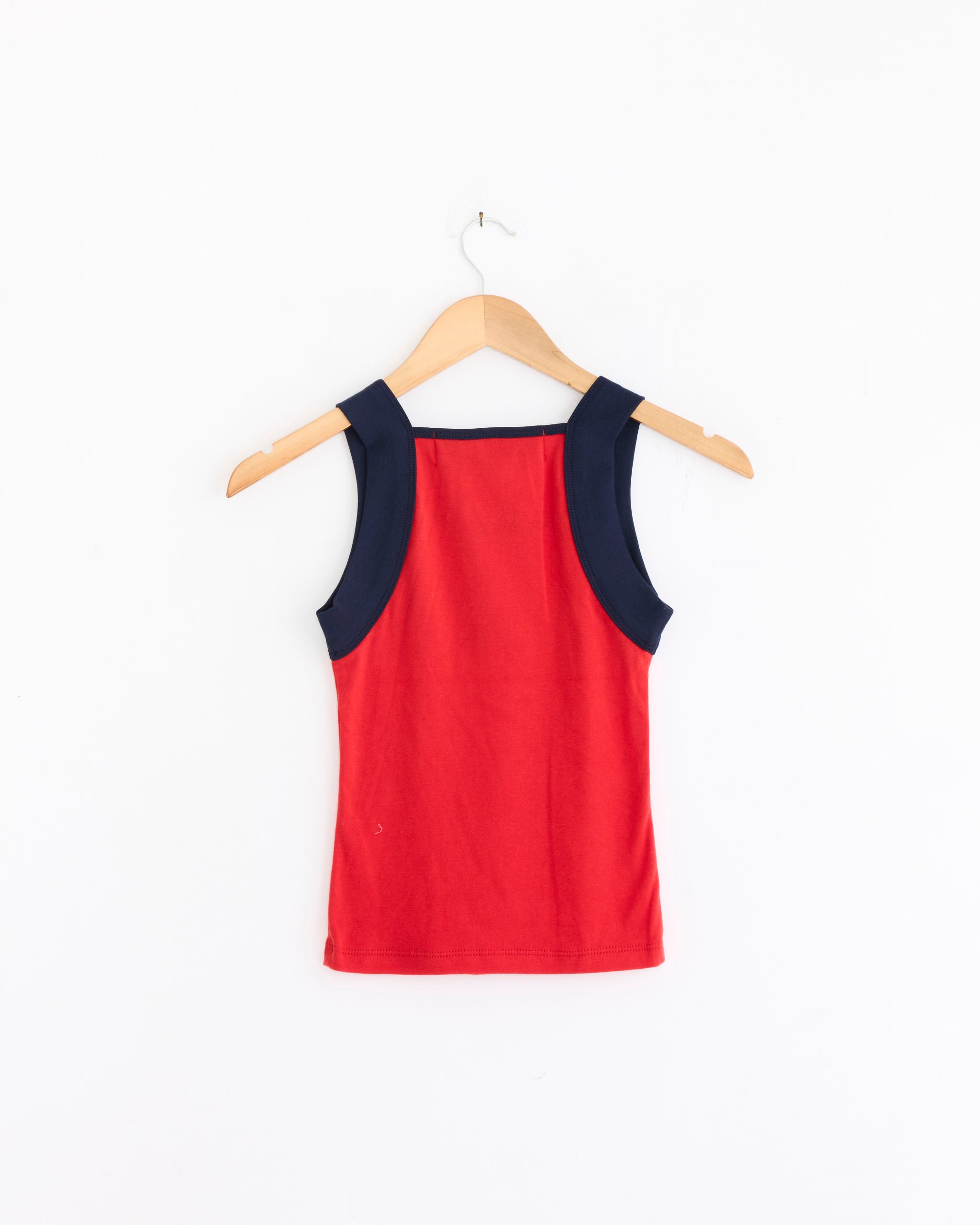 The France Tank Top in Red/Navy by Made Some Sportswear is a sleeveless cotton ribbed tank with wide dark navy straps, shown from the back on a wooden hanger against a plain white background.