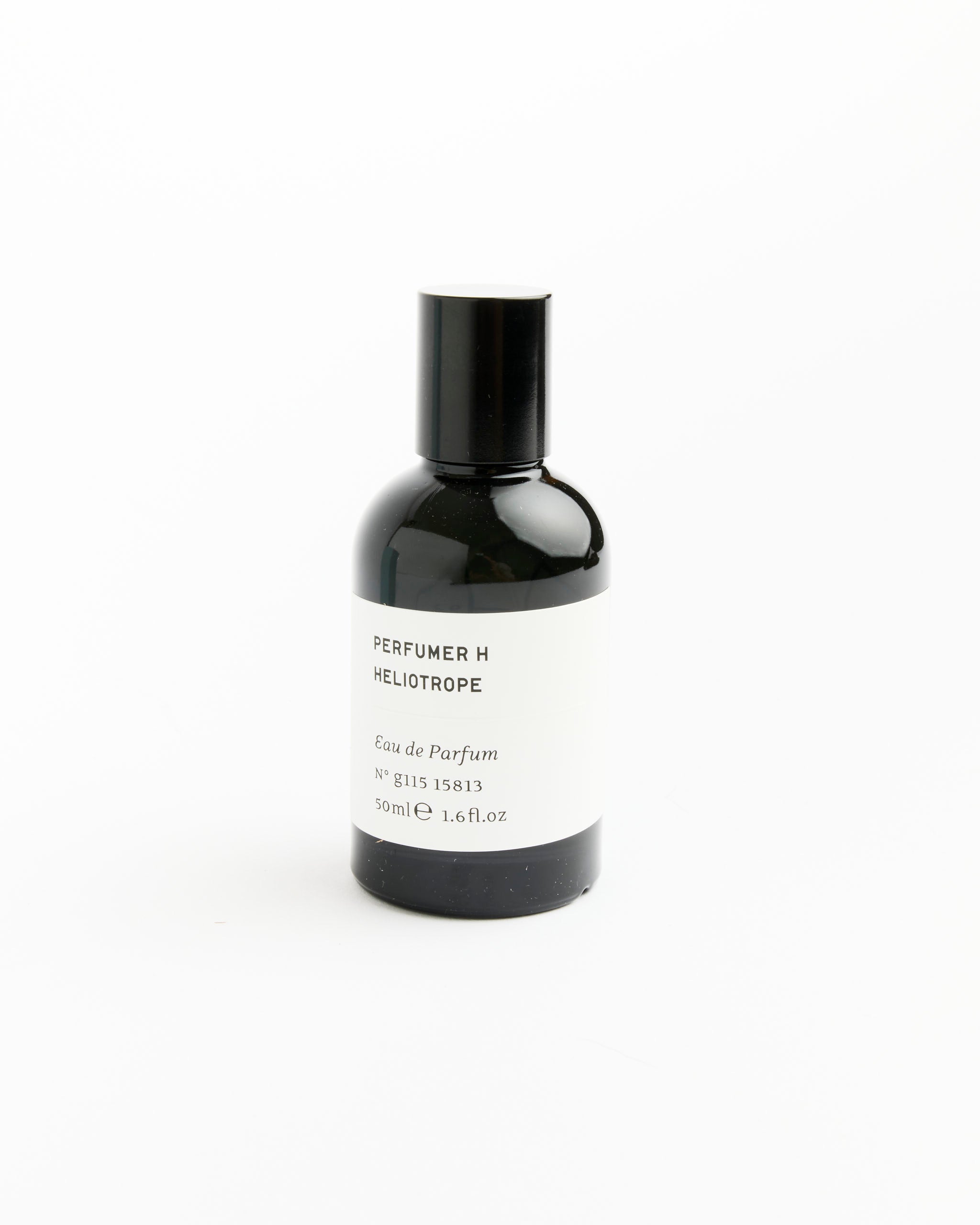 A black bottle of Perfumer H Heliotrope Perfume, 50ml, with a white label and black cap stands upright on a white background—a sleek display for this modern amber scent.