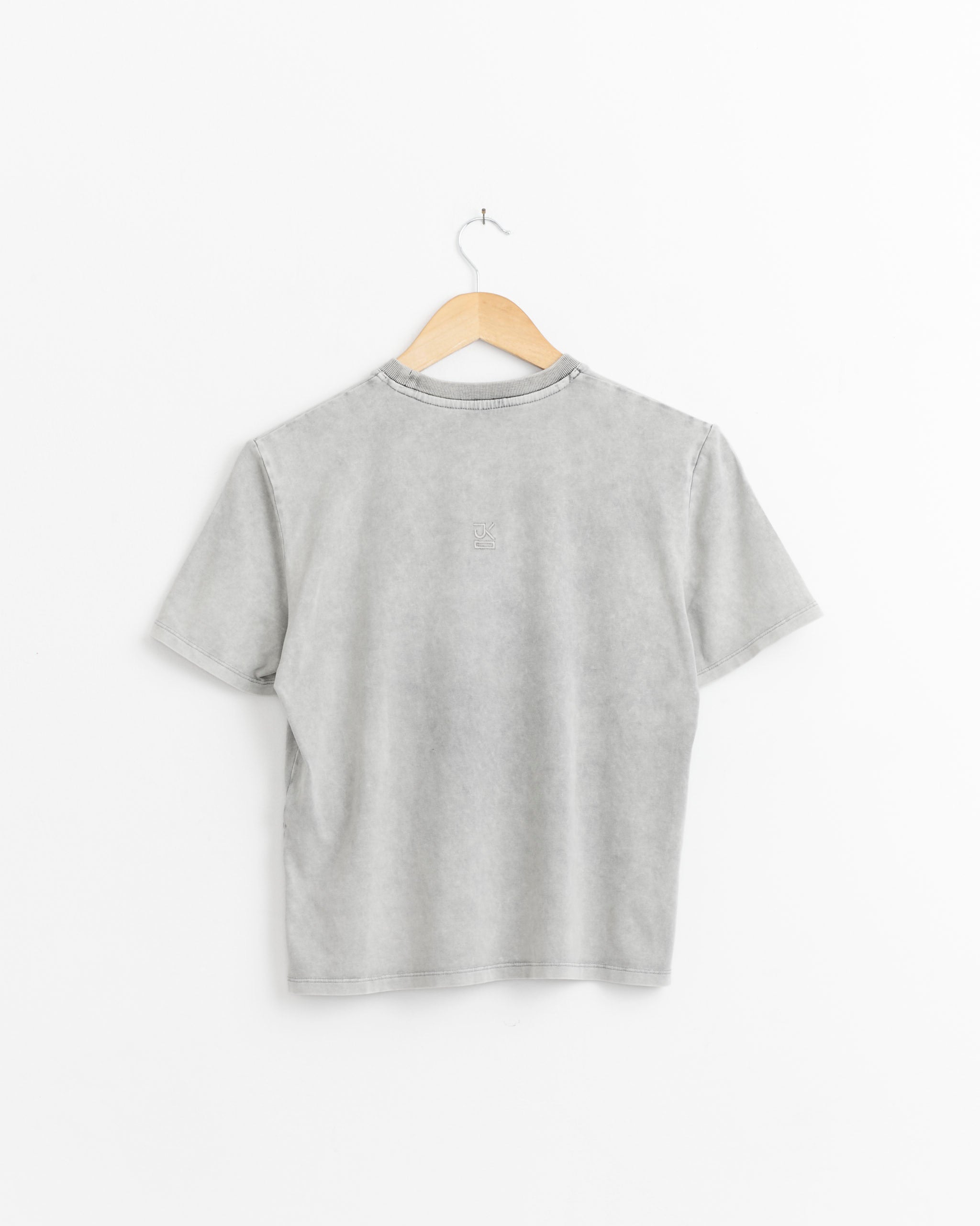 The J. Kim Petal T-Shirt in Ash Grey, featuring short sleeves, is shown from the back on a wooden hanger against a white background.