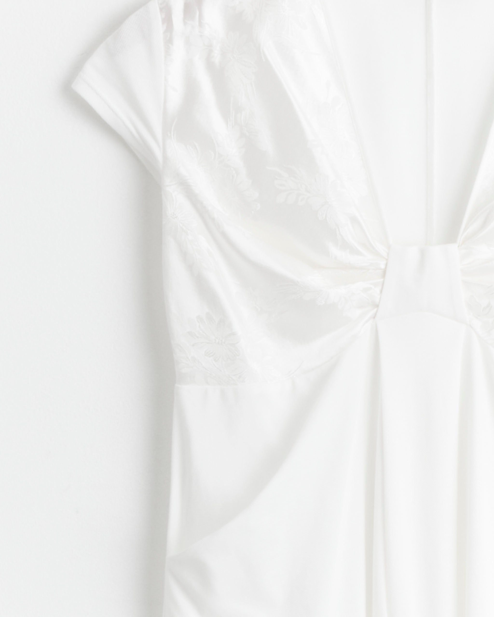 Close-up of the J. Kim Bow Shift Dress in White, featuring cotton piqué fabric with a subtle floral pattern, short sleeves, and gathered bust detail, displayed against a white background.
