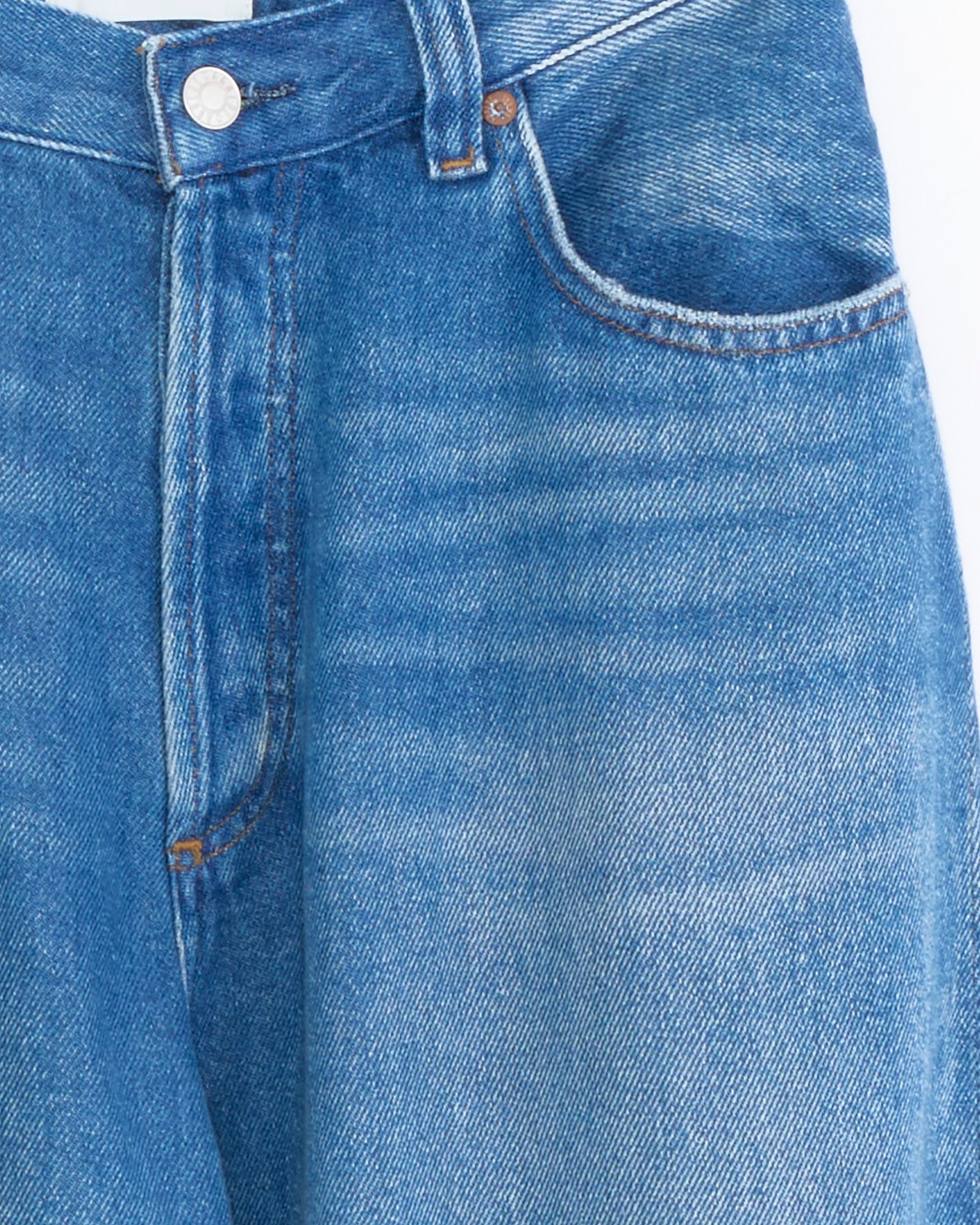 A close-up of the AGOLDE Rounded Baggy Jean in Expression highlights lightweight blue denim with a metal button, belt loop, pocket, and visible stitching details.