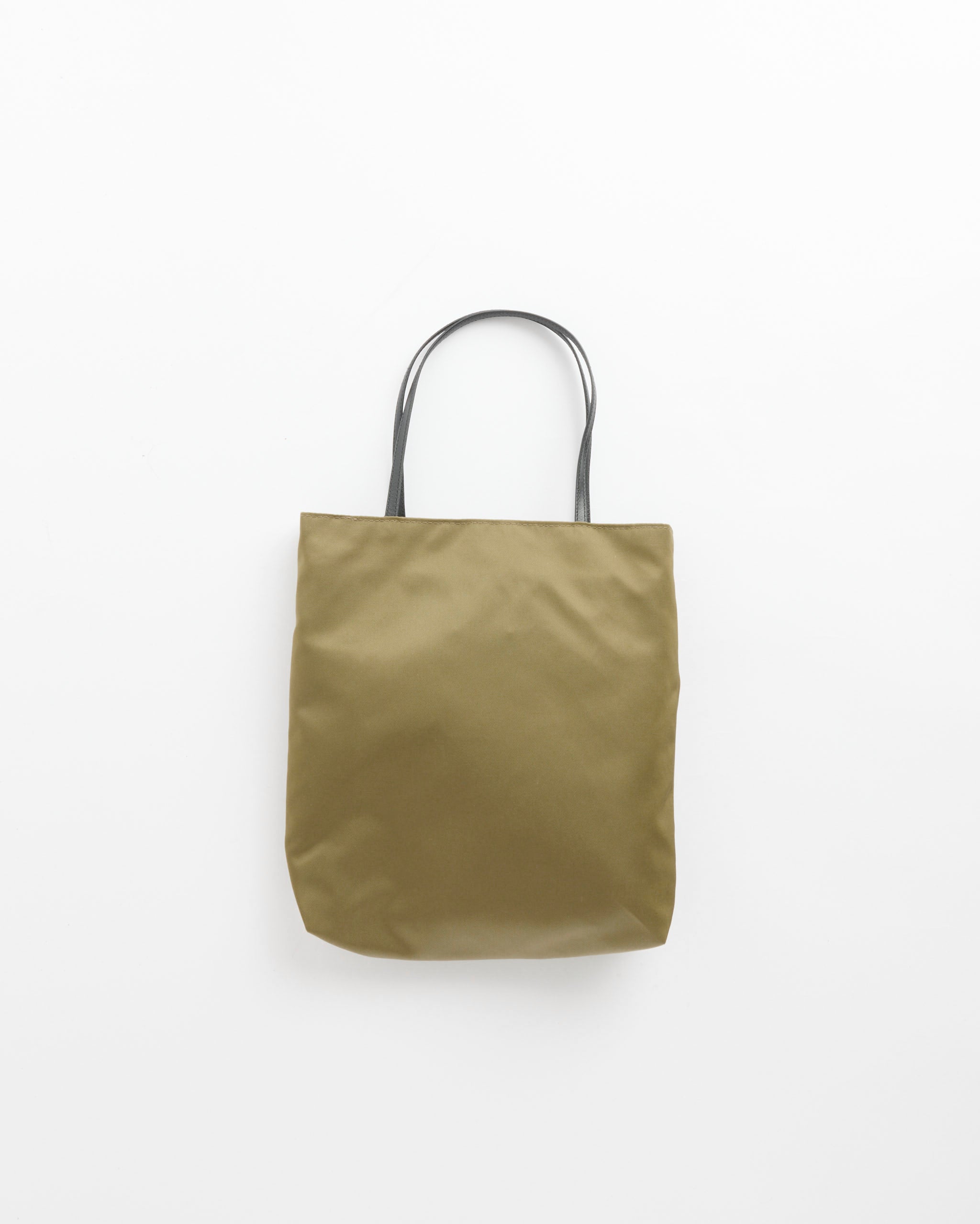 The Thea Bag in Khaki by Valesque, crafted from plain olive-green satin nylon and featuring two sturdy black calf leather handles, is displayed against a white background.