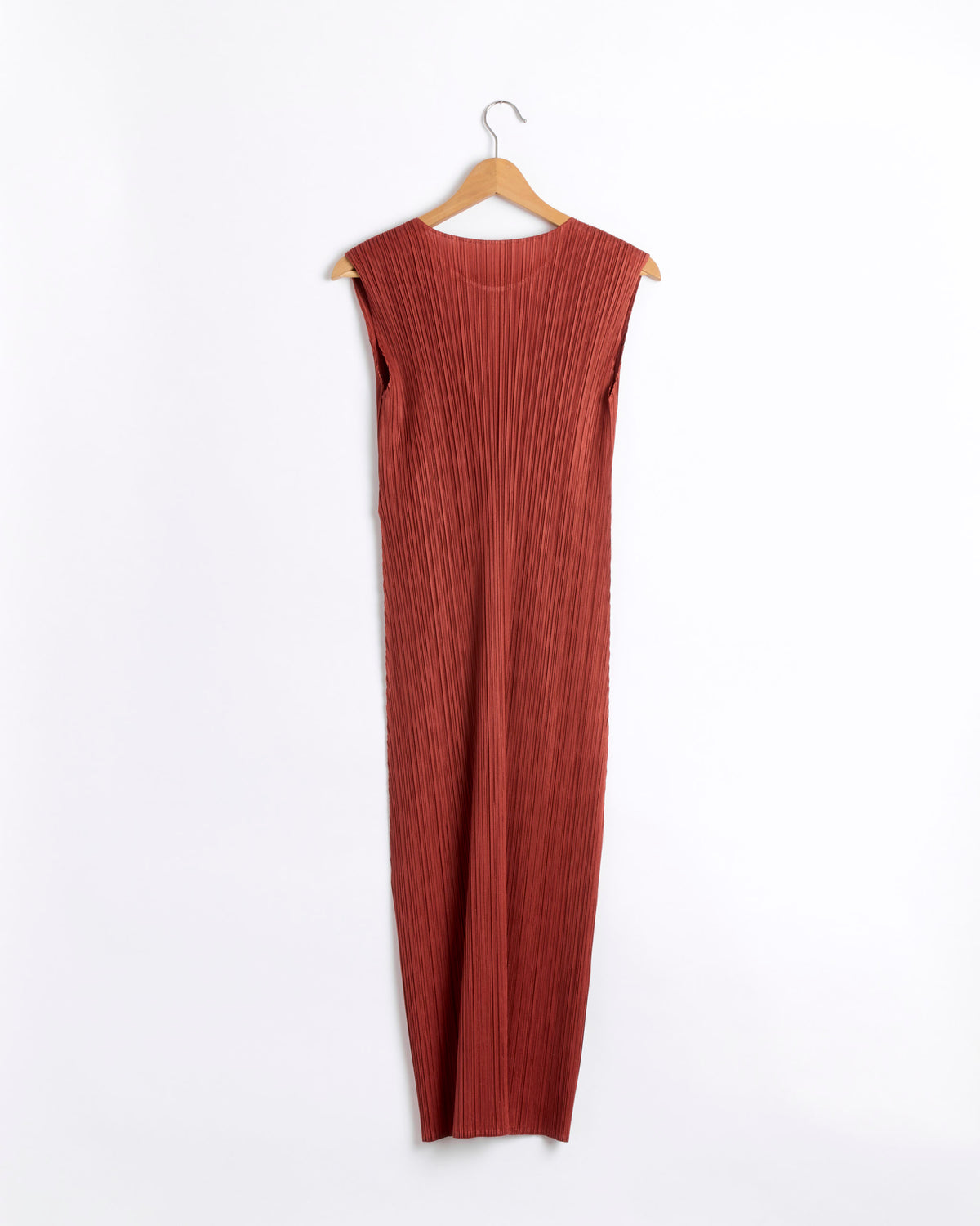 The MC Sept Dress in Red Brown by Pleats Please Issey Miyake is a sleeveless, ankle-length pleated polyester dress in a rust hue, featuring vertical pleats as part of the Monthly Colors September collection. It is displayed on a wooden hanger against a plain white background.