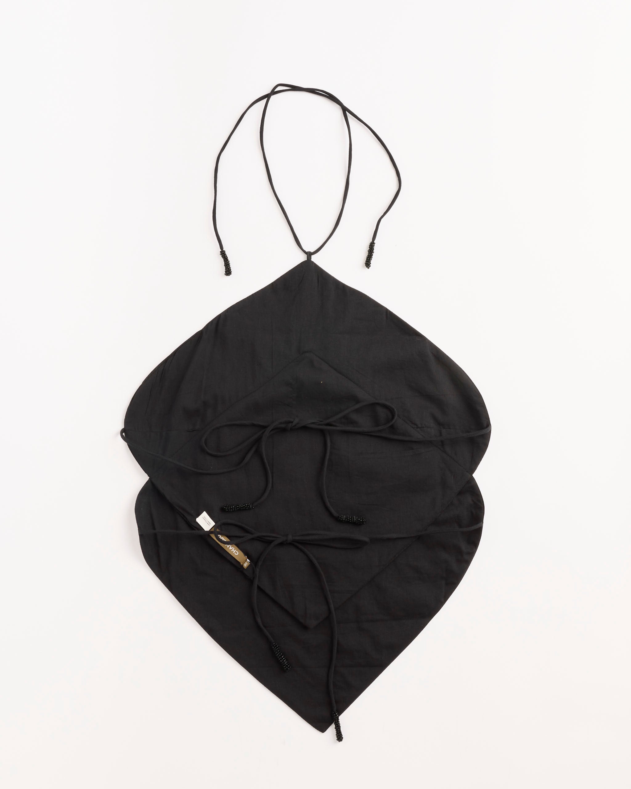 The Chan Luu Napkin Dupioni Halter Top in Black, featuring a leaf-shaped design with two layers and adjustable ties, is shown on a plain white background. A small white label accents one side, evoking sleek elegance.