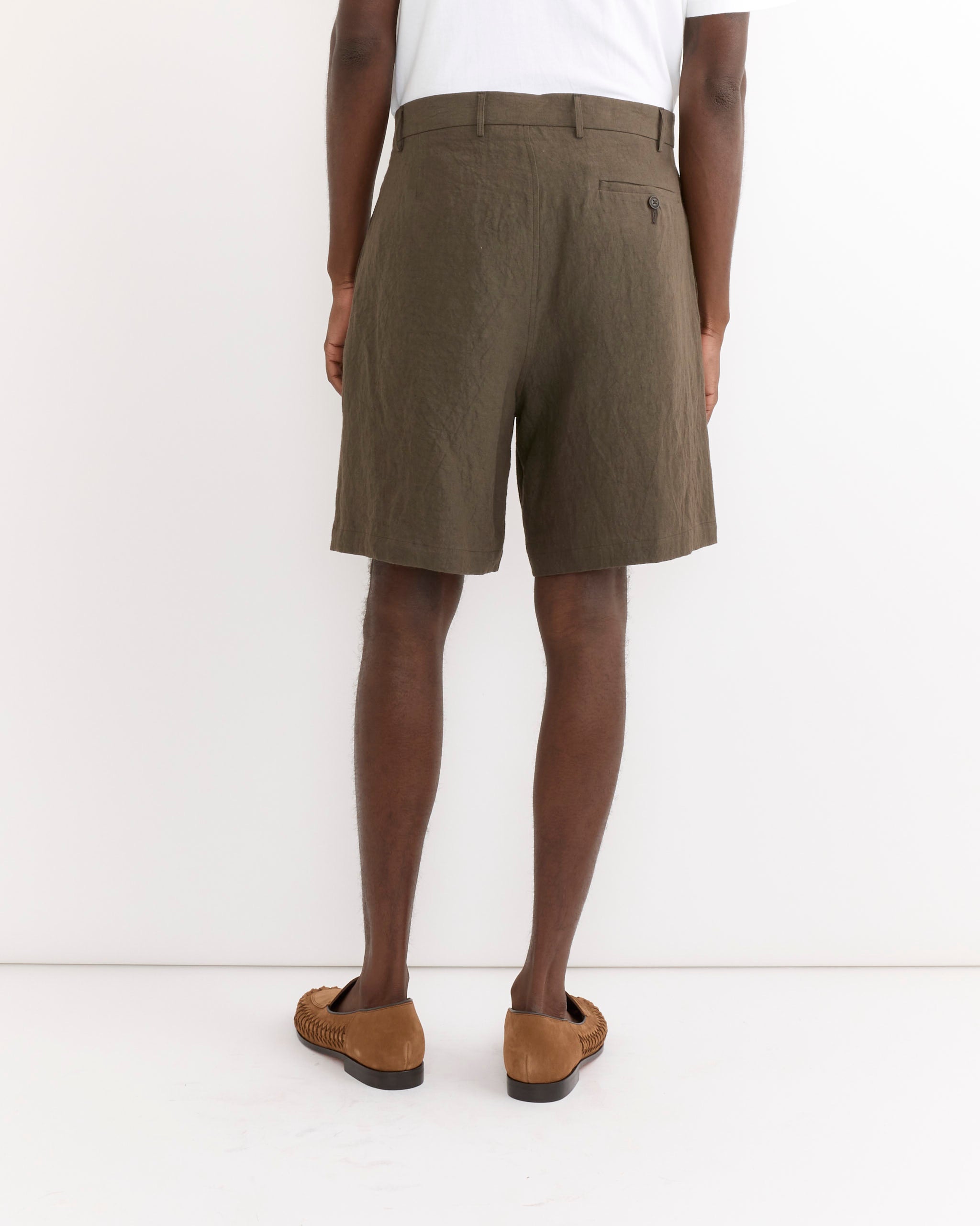 A person wearing a white shirt, SMOCK Arroyo Short in Sun Dried Linen Tobacco, and brown woven loafers stands against a white background, shown from the back.