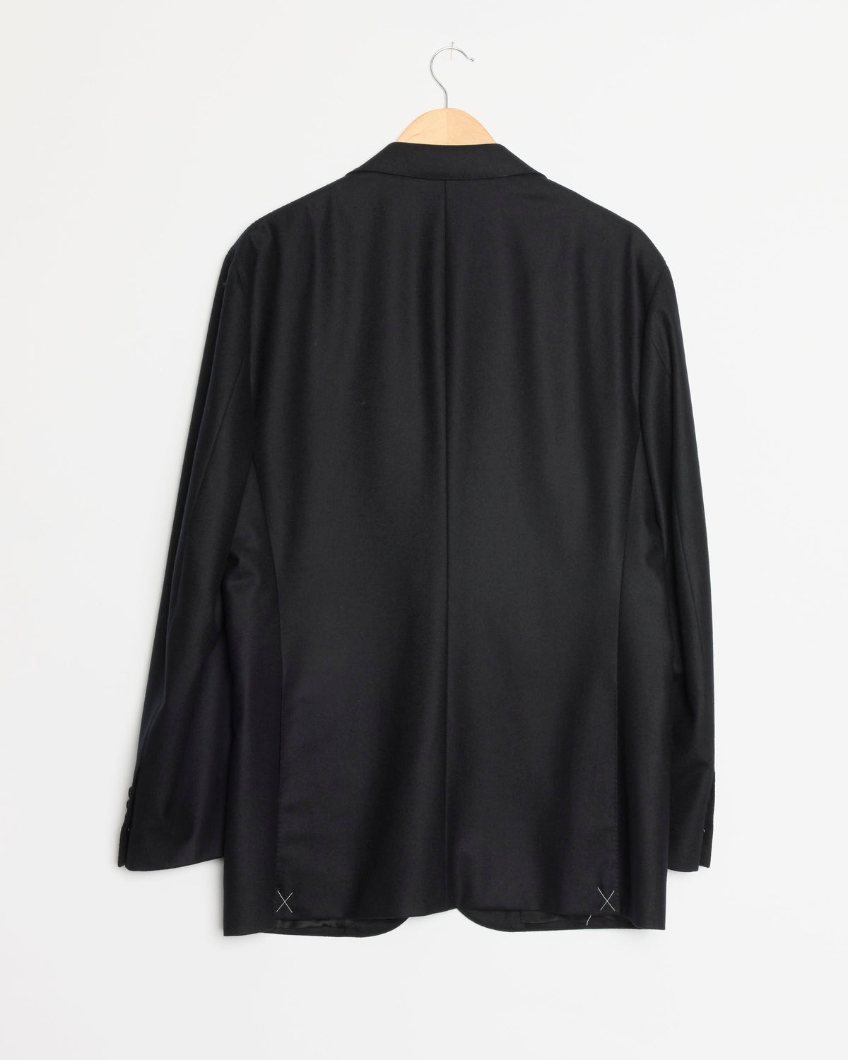 The Heavy Flannel SB Jacket in Black by Salon C. Lundman hangs on a wooden hanger against a plain white wall, displayed from the back.