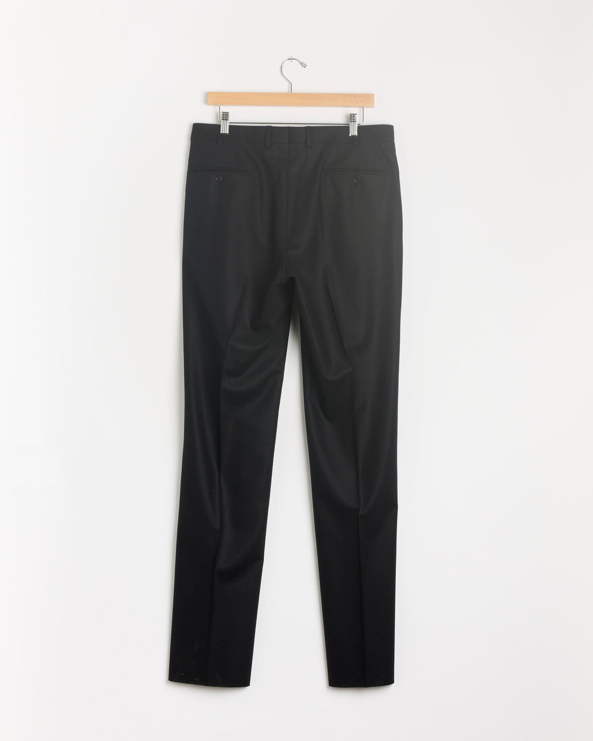 The Double Pleat Flannel Trouser in Black by Salon C. Lundman hangs on a wooden hanger against a plain white background.