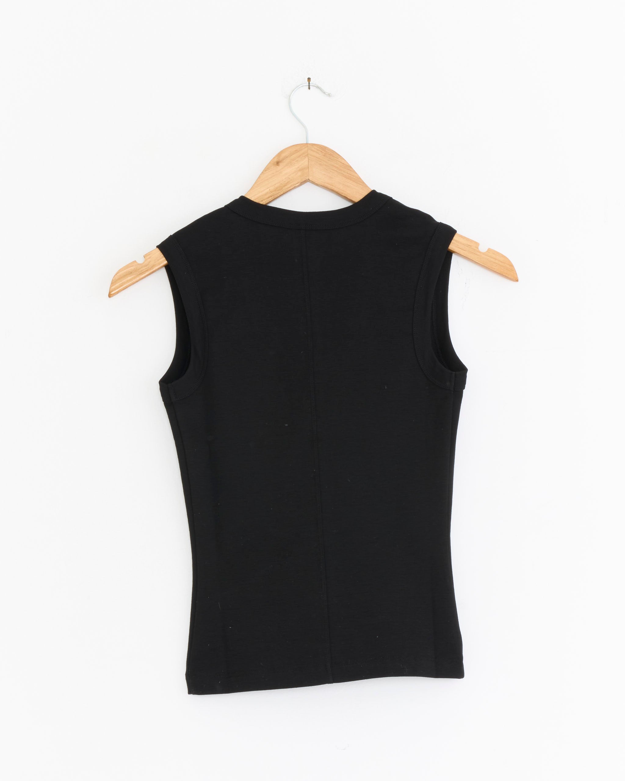 The Dewi Tank in Black by FLORE FLORE is shown from the back, sleeveless and displayed on a wooden hanger against a plain white background.