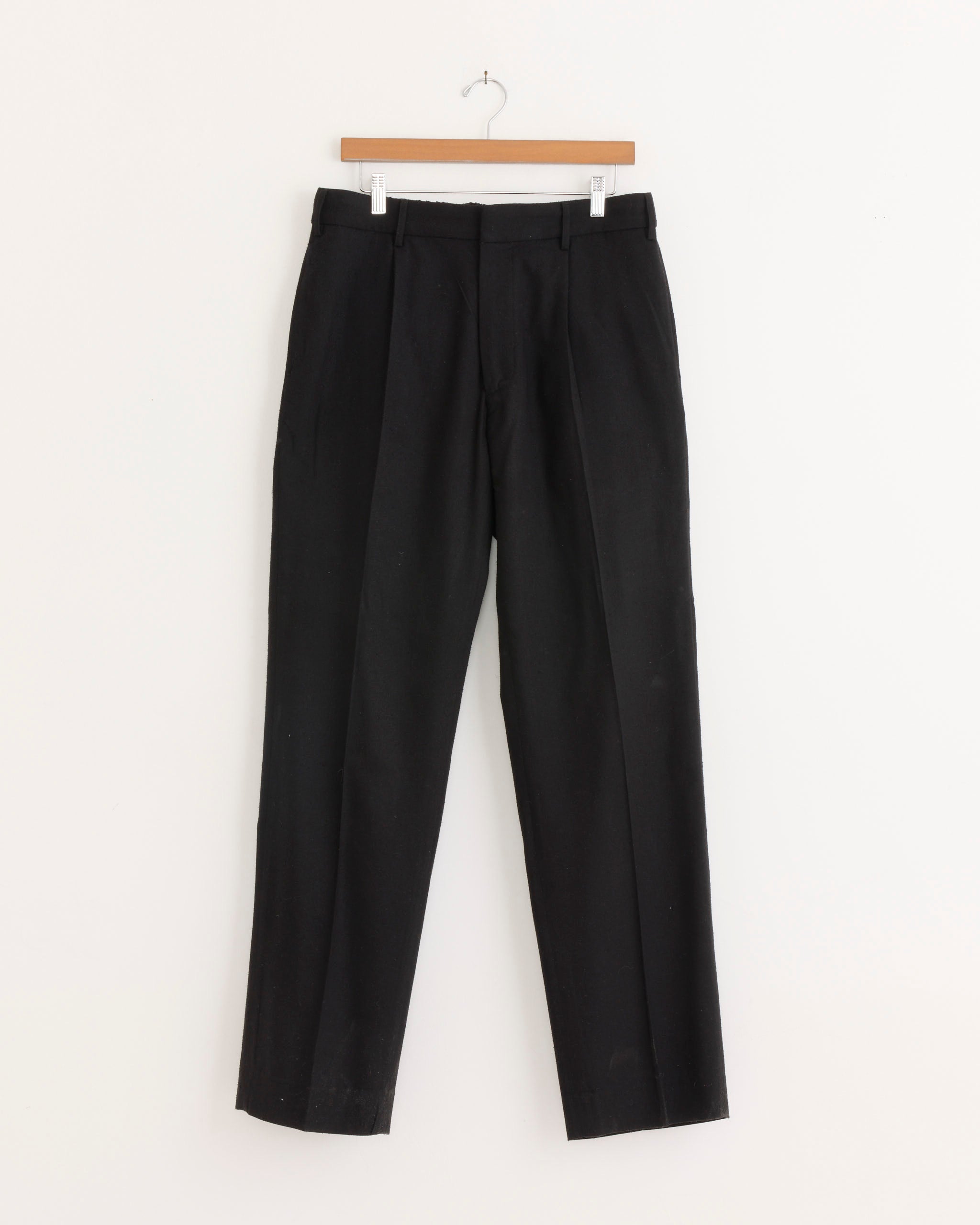 The West Coast Pant in Raw Silk Black by SMOCK hangs on a wooden hanger against a plain white background.