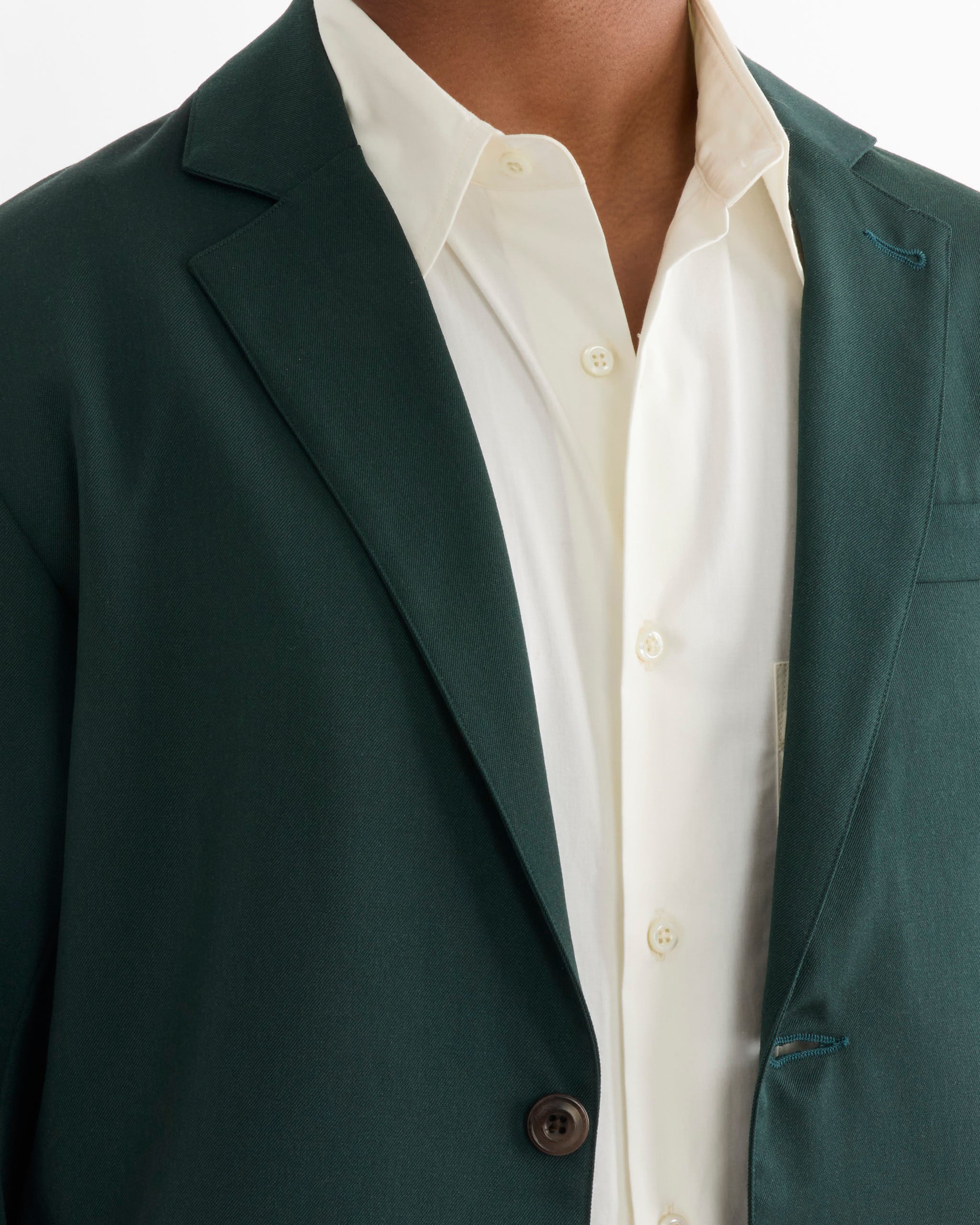 A person wearing the SMOCK Blazer in Wool Gabardine Dark Green over a white button-up shirt, photographed from neck to chest to highlight the collar and lapel details.