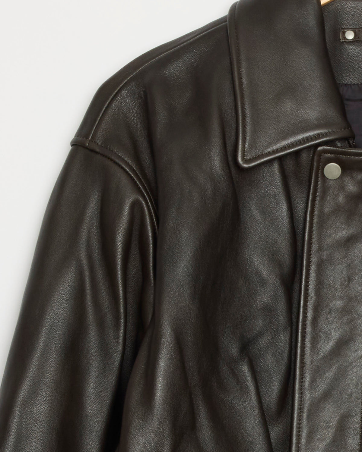 Close-up of the ssstein 1555 Jacket in Vintage Black hanging on a hanger, highlighting the collar, shoulder, and part of the upper sleeve.