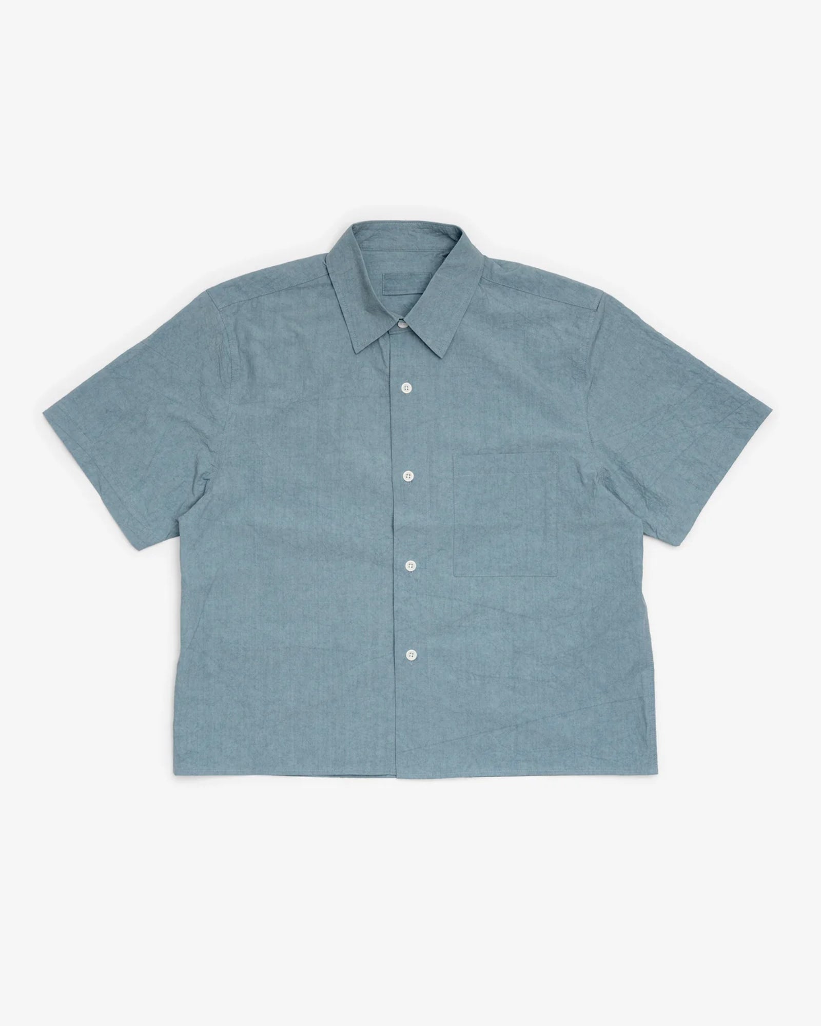 The James Coward Short Sleeve Shirt in Blue, crafted from airy Japanese typewriter cloth, features a pointed collar and four white buttons. Designed for men, it is shown laid flat against a white background.