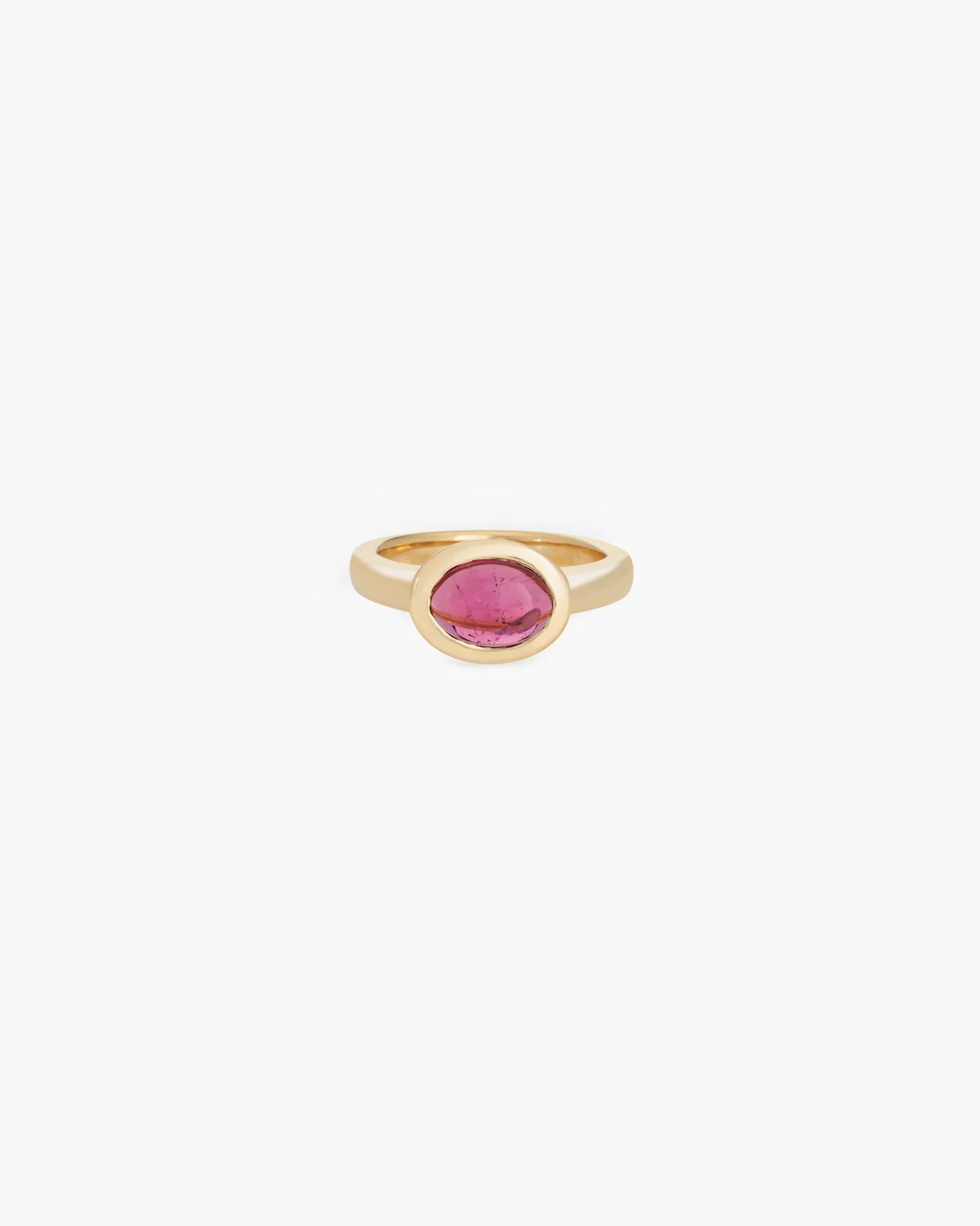 The Cabochon Ring in 18K by Kathryn Bentley features an oval pink tourmaline gemstone in a simple bezel setting, handcrafted in yellow gold and showcased on a white background.