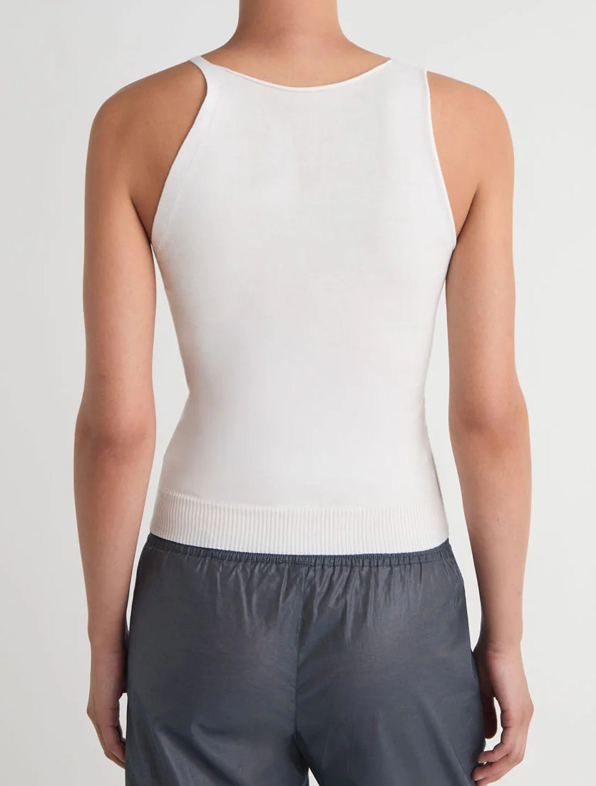Model wearing the Paloma Wool Lani Tank in Off White, featuring a high neckline, paired with dark gray pants, shown from the back against a plain light background.