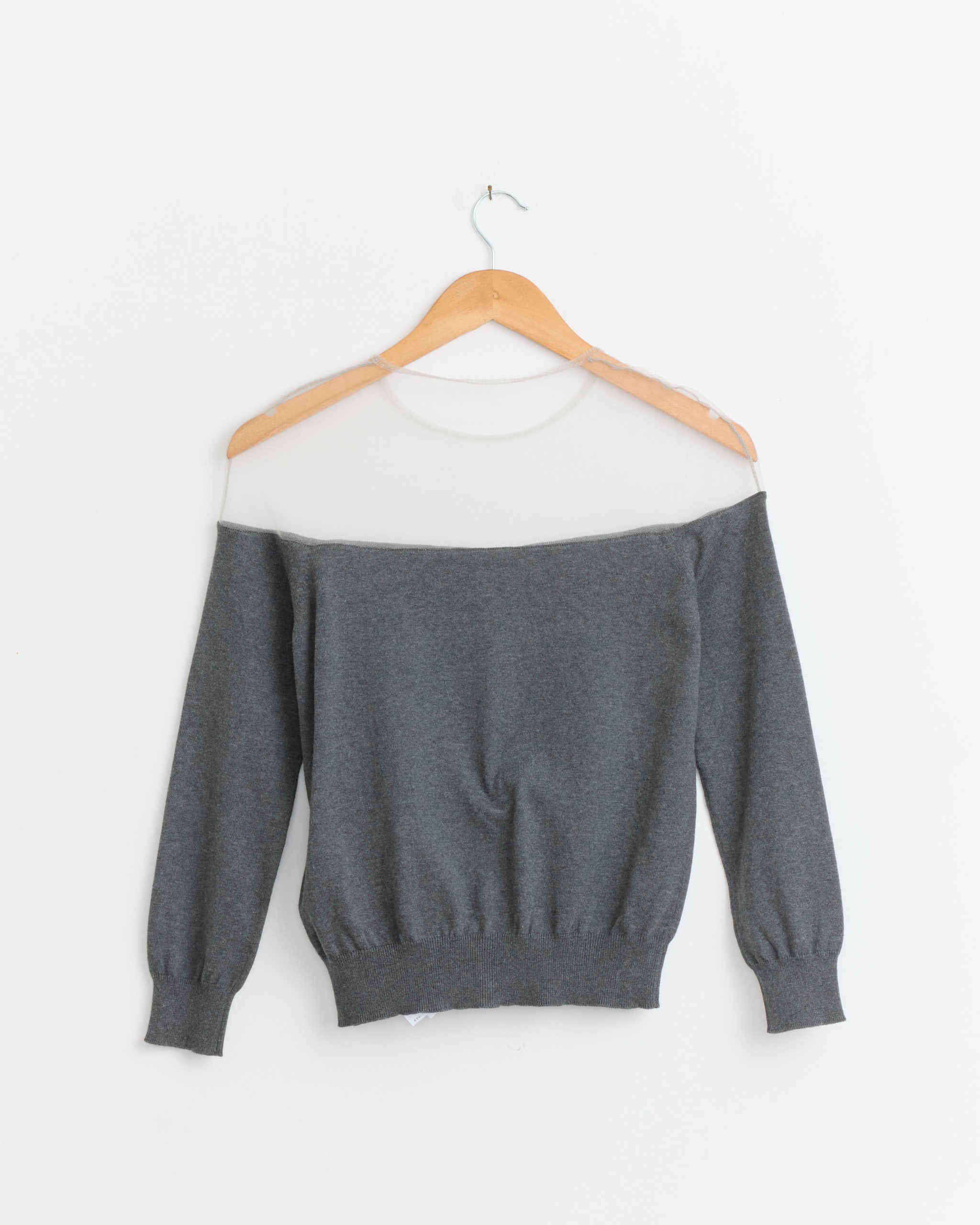 The Knit Cardigan in Dark Grey Melange by MM6 Maison Margiela features a sheer white mesh neckline and is displayed on a wooden hanger against a white background, reflecting the brand's signature minimal aesthetic.