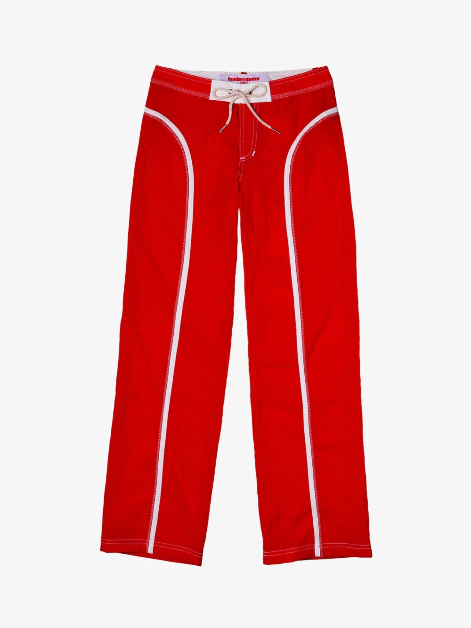 The Pant in Red/White by Made Some Sportswear features a bright red color with white piping detail along the seams and a white drawstring at the waistband. These lightweight nylon pants are displayed on a plain white background.