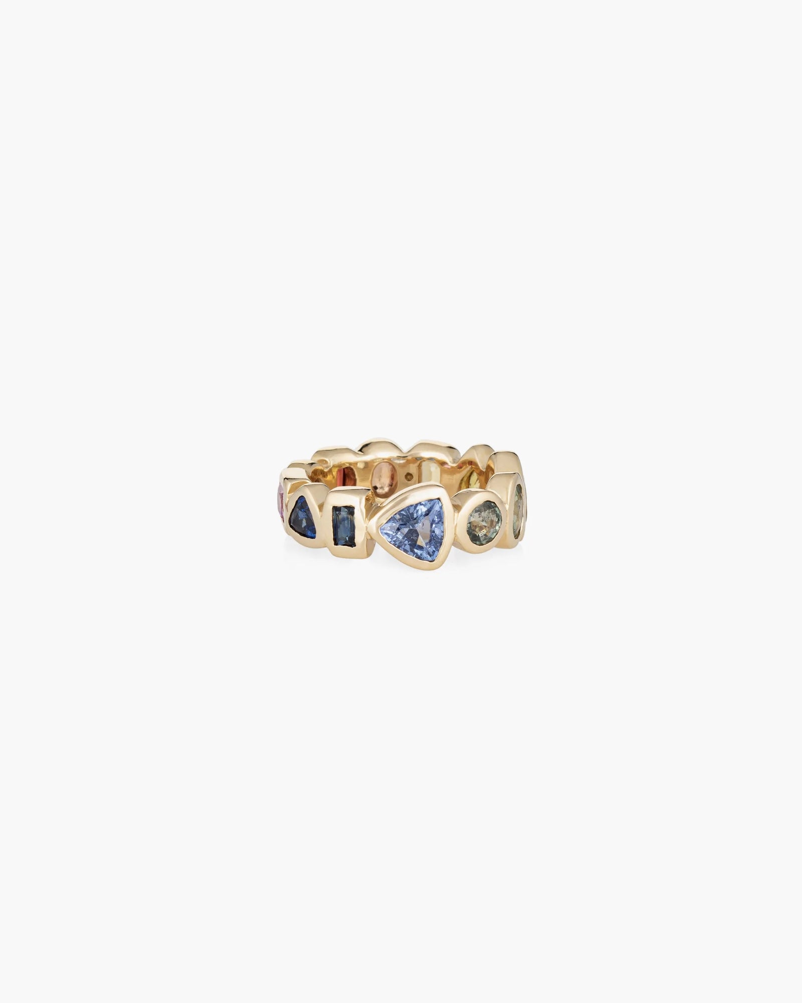 The Confetti Band by Kathryn Bentley is a handmade 14K gold ring featuring bezel-set, irregularly arranged blue and green sapphires in various shapes around the band.