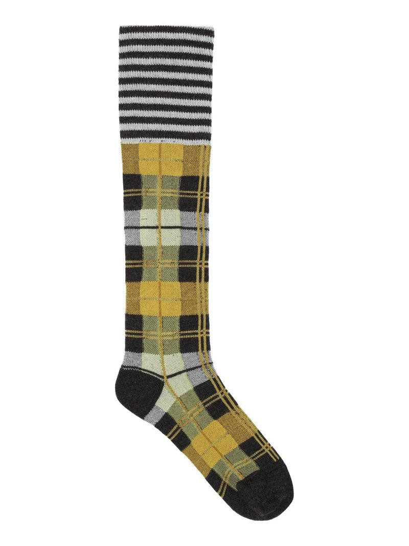 A single Ribbit Knee Sock in Brown Green Dashed Checks by Henrik Vibskov, featuring bold black and white stripes at the top and a striking plaid pattern in yellow, green, gray, and black on the lower part and foot.