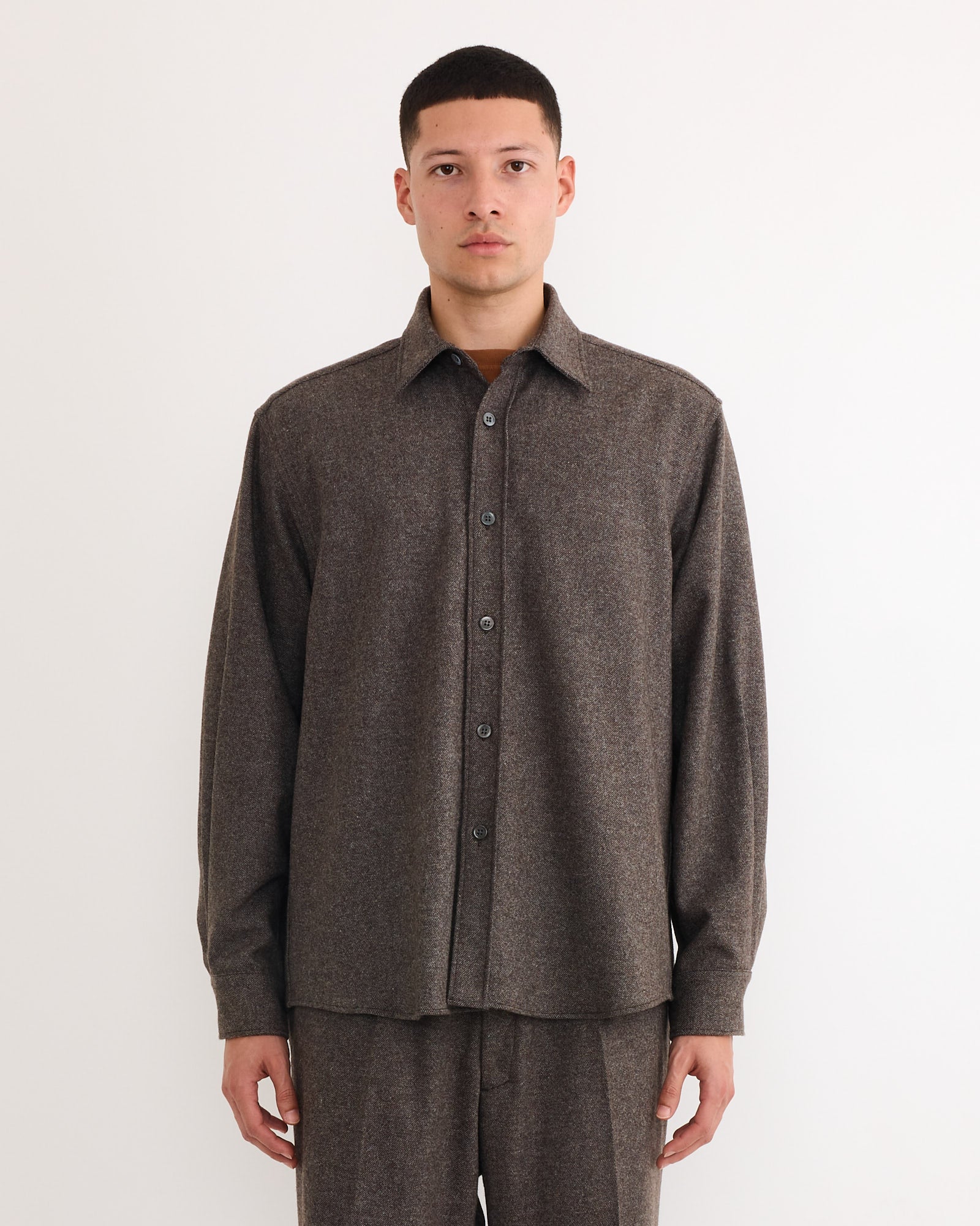 A person stands against a plain white background, wearing the SMOCK Davis Shirt in Cashmere Wool Brown with matching brown pants, looking straight at the camera with a neutral expression.