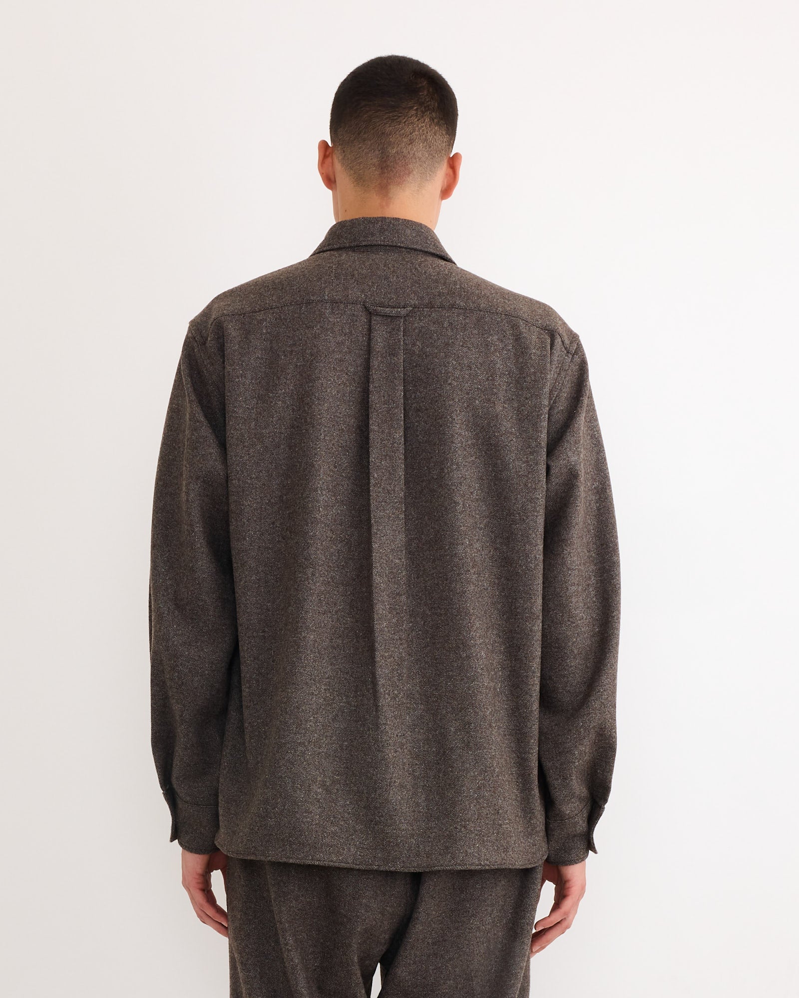 A person faces away from the camera wearing the SMOCK Davis Shirt in Cashmere Wool Brown with matching pants, made in Los Angeles, set against a plain white background.