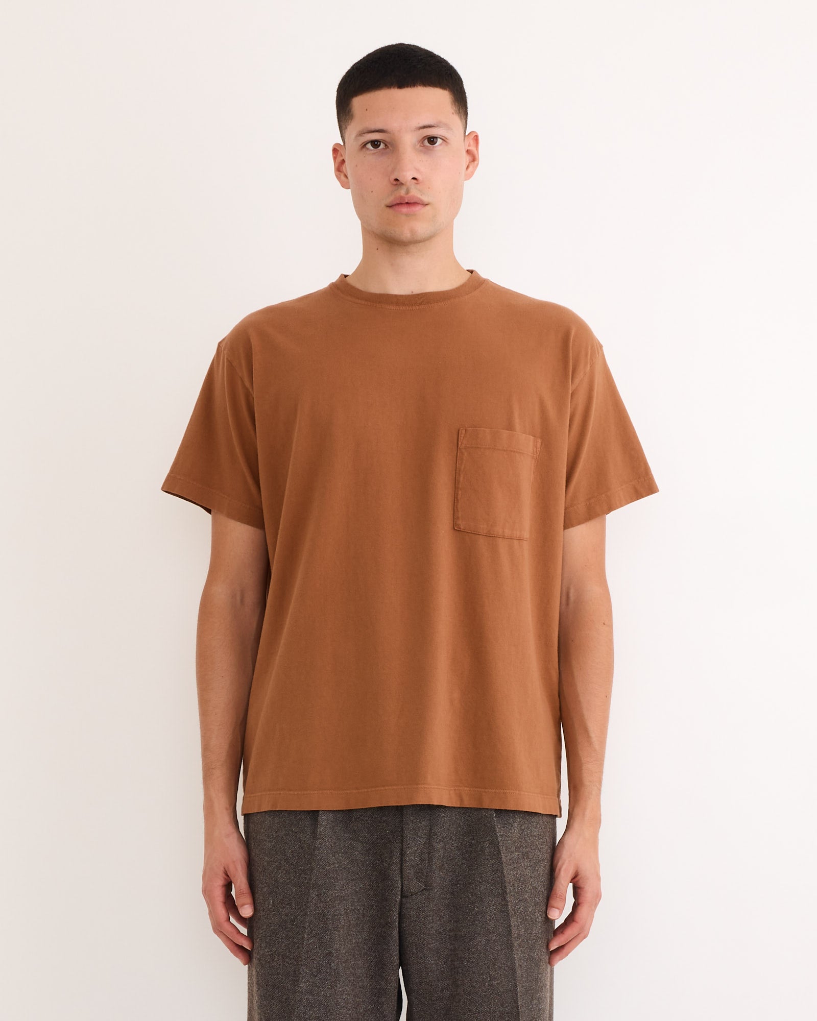 A person stands facing forward against a plain white background, wearing the SMOCK Bachelor Pack in Caper/Port/Chai and gray pants.