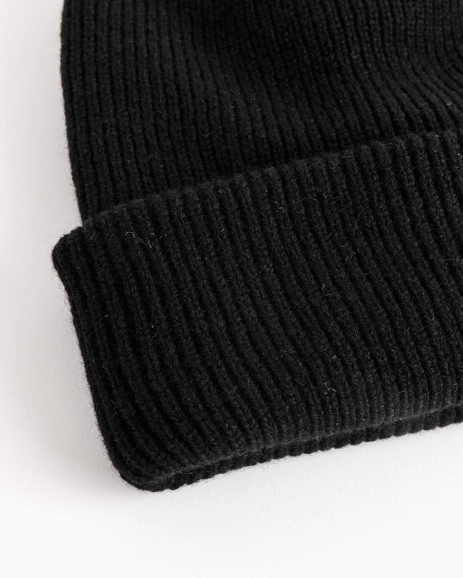 Close-up of the SMOCK Cashmere Beanie in Black, featuring rib-knit 100% cashmere fabric with a folded cuff, displayed on a white surface.