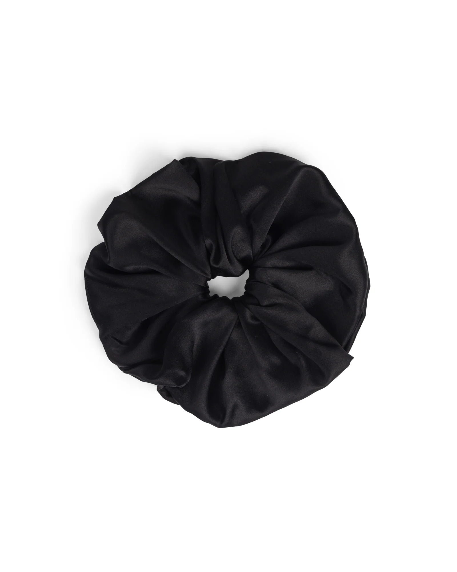 The Hai Big Scrunchie in Black is displayed on a white background. This stylish hair accessory features smooth, shiny satin fabric gathered around an elastic band in a ruffled circle.