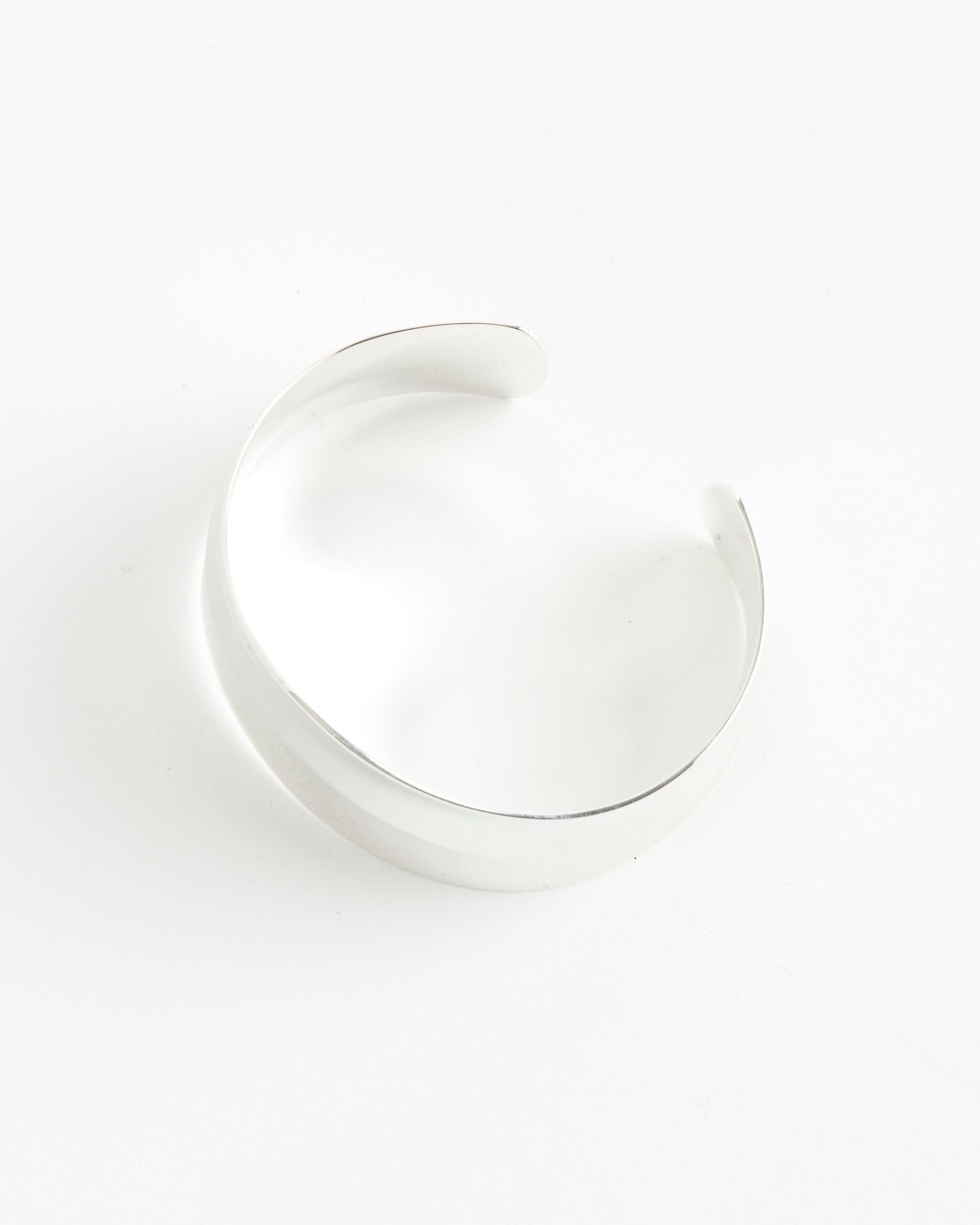 The Sophie Buhai Petite Wave Cuff is a sleek, wide silver bracelet with a smooth, polished finish, shown on a white background. For sizing or fit questions, our online chat team is here to help.