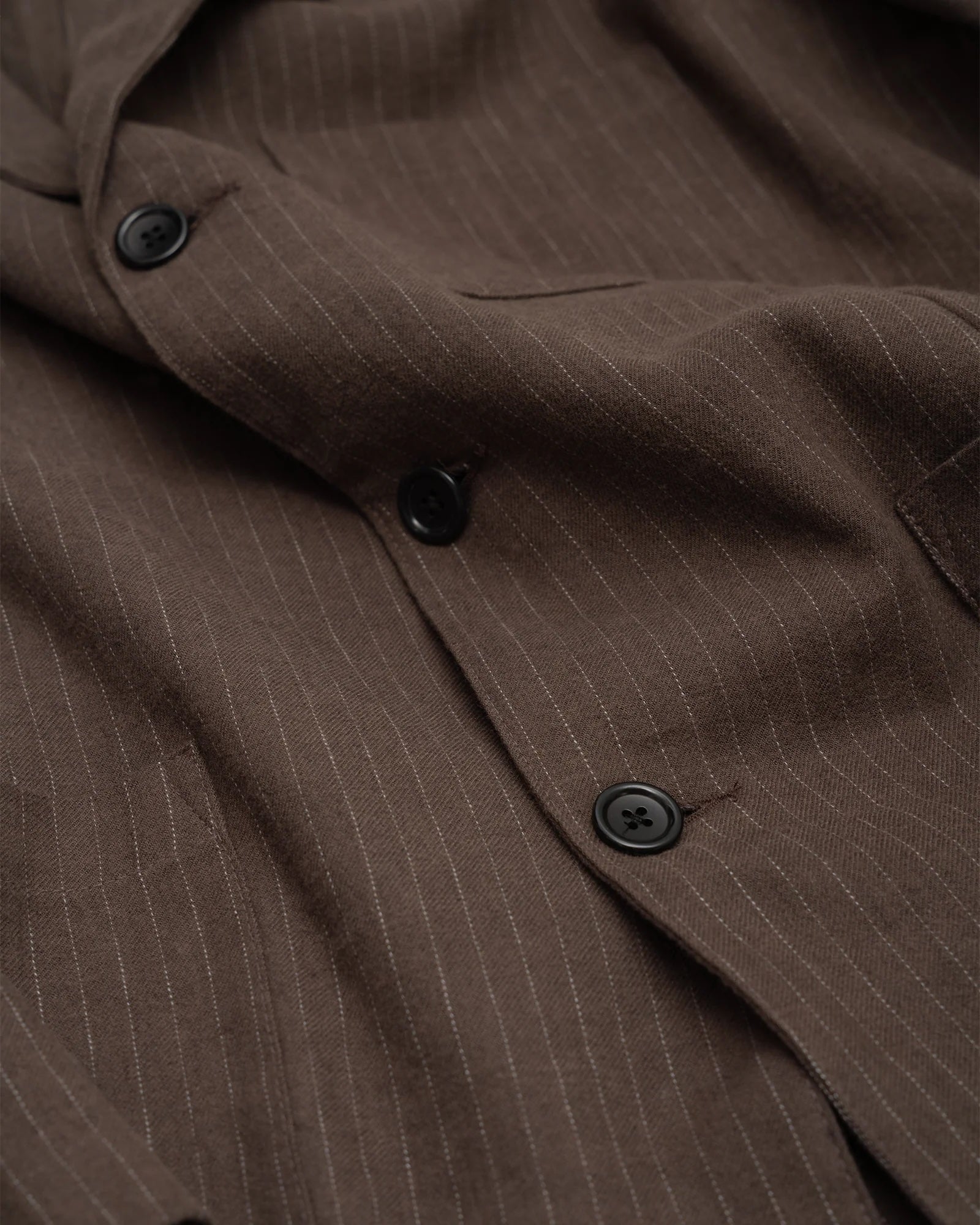 Close-up of the Carry On Jacket in Dark Brown by James Coward, featuring cotton linen wool twill fabric, black buttons, soft texture, and subtle vertical stripes.