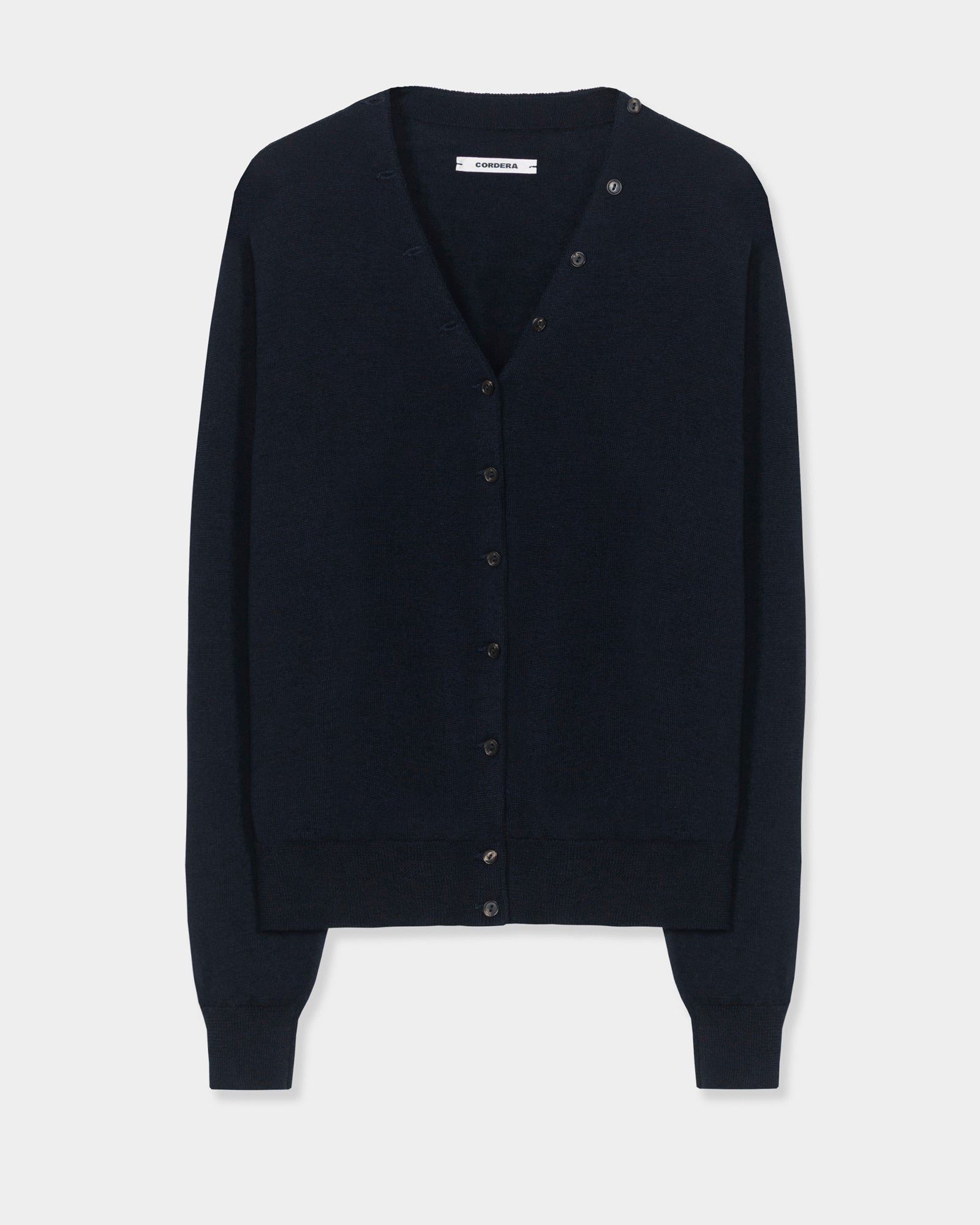 A navy V-neck button-up merino wool cardigan by CORDERA, featuring long sleeves with ribbed cuffs and hem, displayed on a plain white background.
