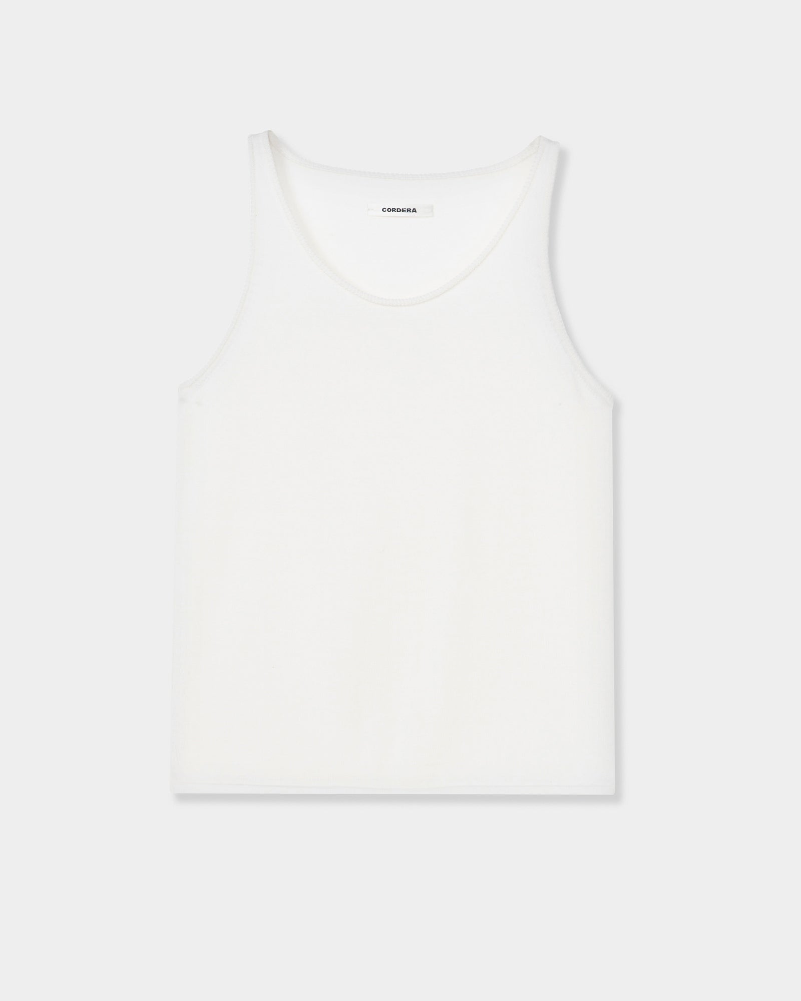 The CORDERA Merino Wool Tank Top in White is displayed flat on a light gray background. Crafted from ultrafine Merino wool, this minimalist tank features a round neckline with no visible patterns or designs, offering a luxurious and understated appearance.