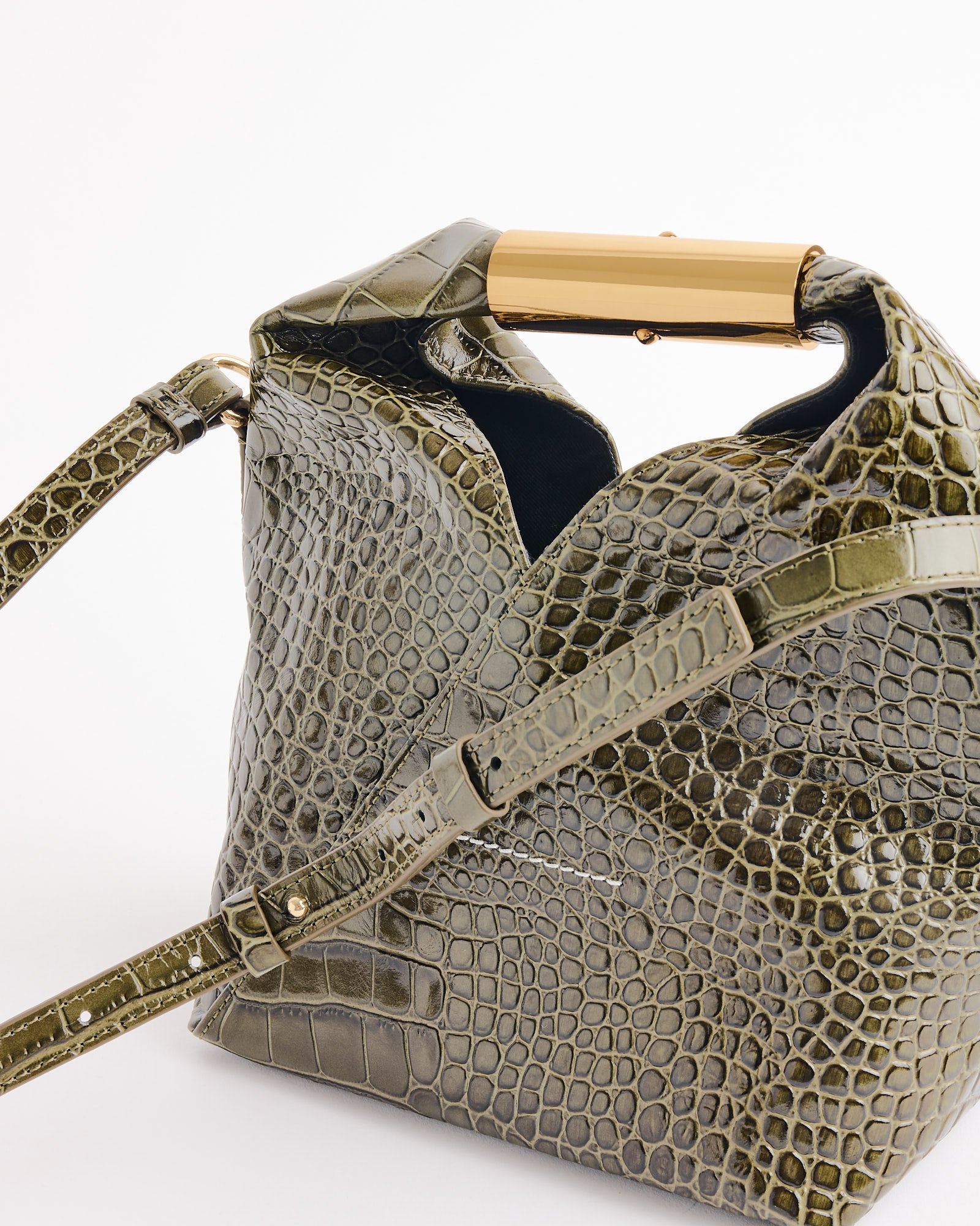 The MM6 Maison Margiela Japanese Small Bag in Olive is a glossy crocodile-print handbag with a gold metal handle and matching adjustable strap, inspired by Japanese shoulder bag design and shown against a white background.
