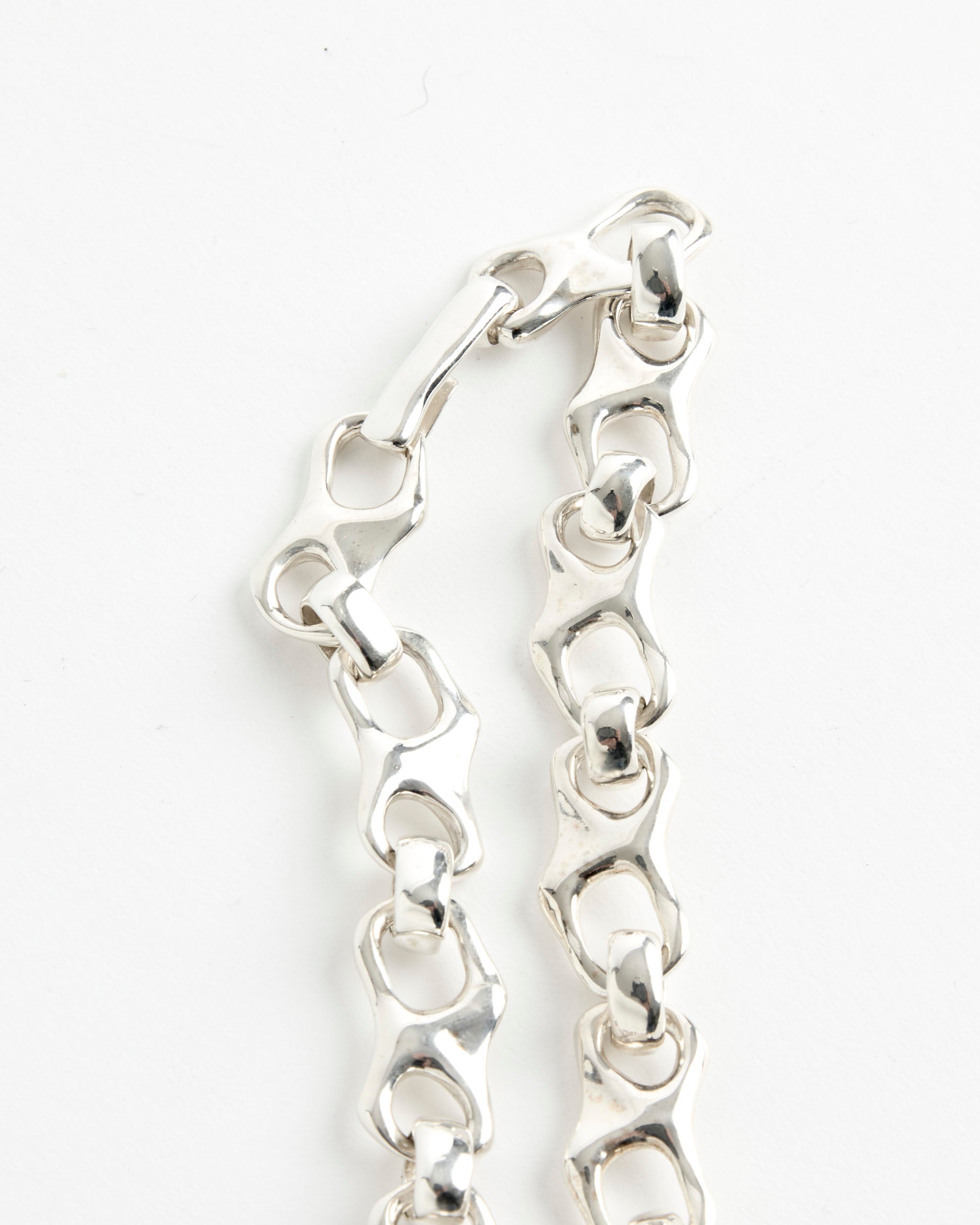 A close-up of the Faris Tab Collar: a shiny silver chain with uniquely chunky links and a clasp, displayed on a white background. Available in various sizes—contact our online chat for help finding your perfect fit.