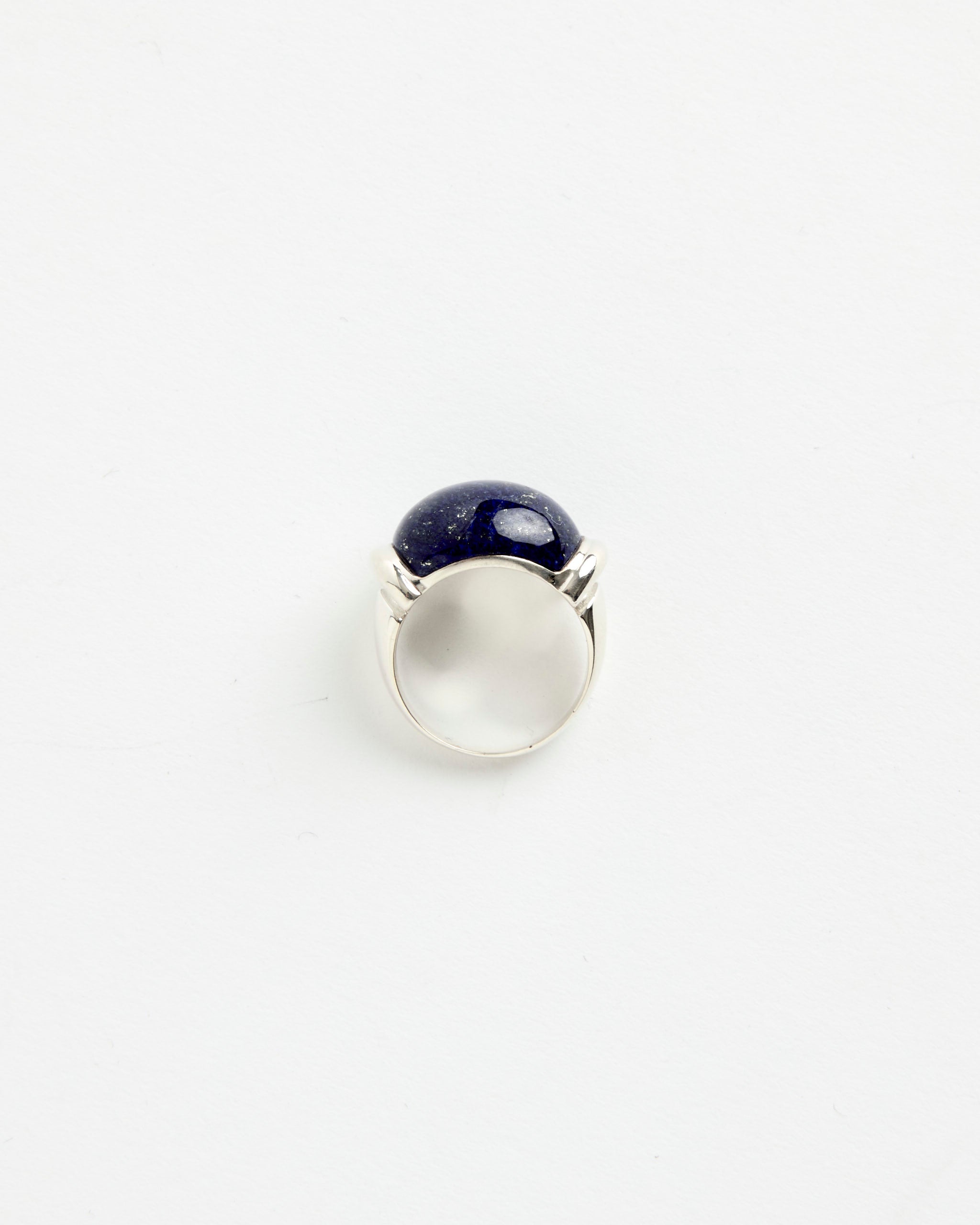 The Sophie Buhai Demain Ring, crafted in sterling silver and topped with a large round dark blue stone, is photographed against a plain white background, reminiscent of the brand's signature lapis designs.