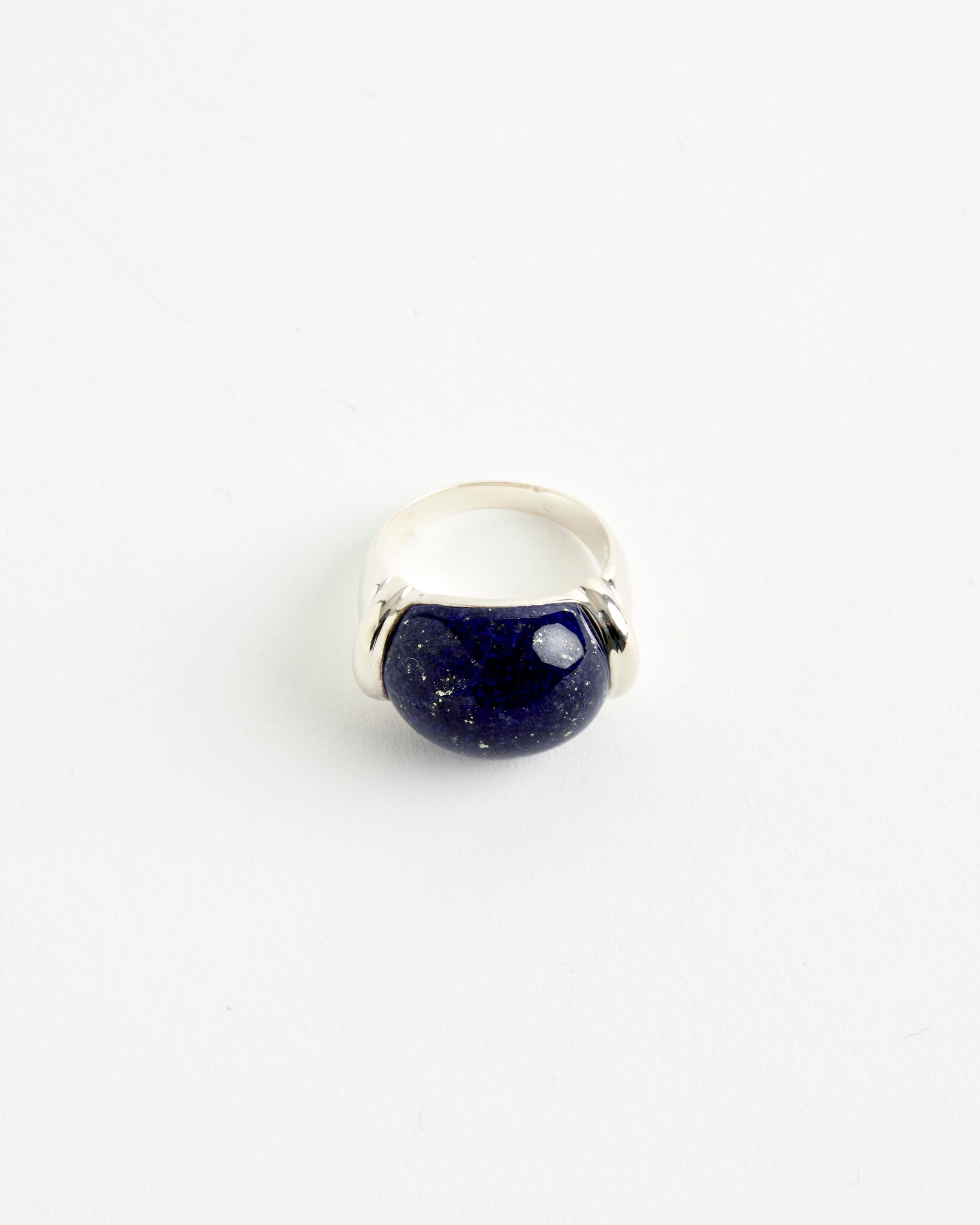 The Sophie Buhai Demain Ring features a large, rounded dark blue stone with subtle specks, set in a minimalist sterling silver band, and is photographed on a plain white background.