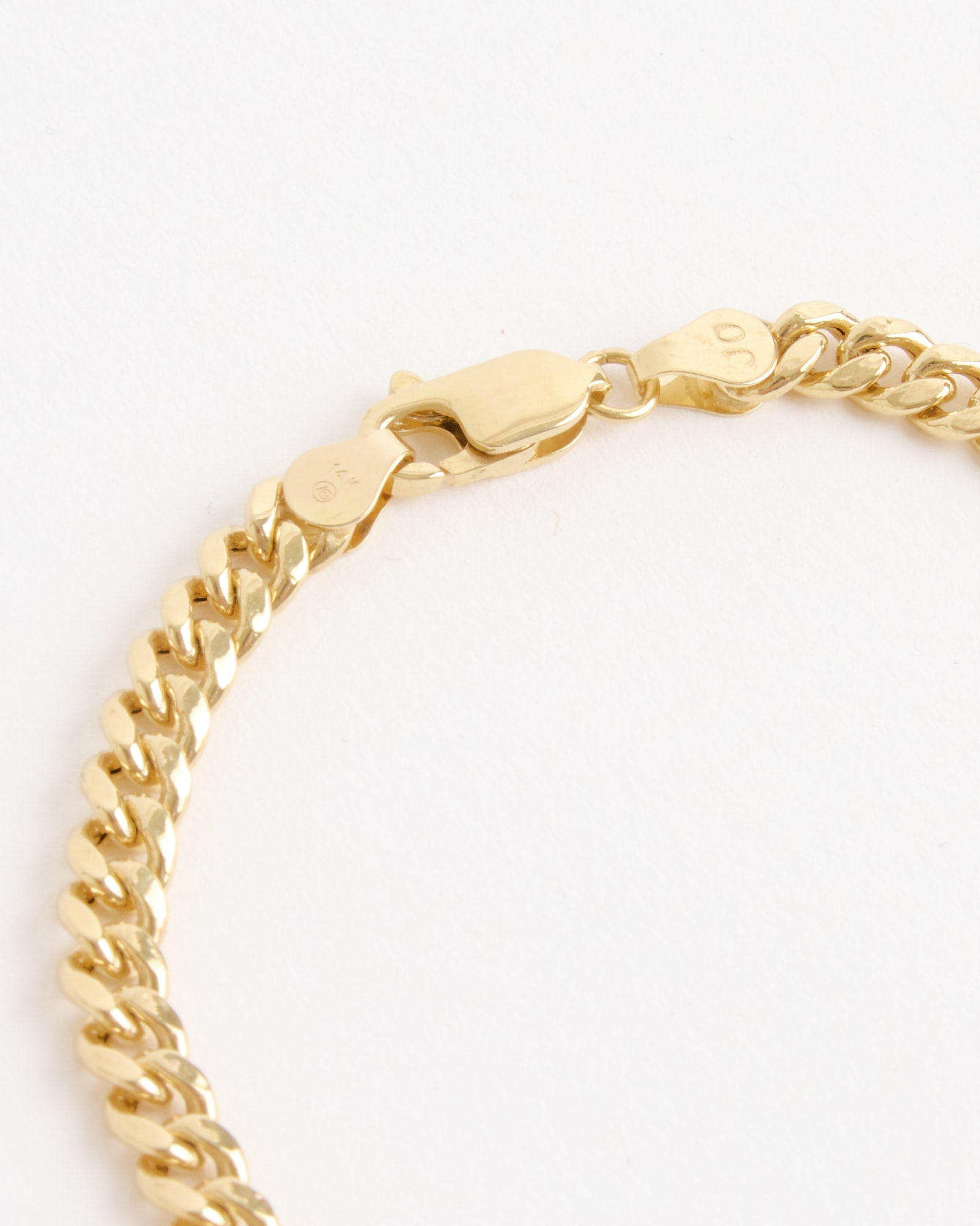 A close-up of the SHOPDELAGOLD Chunky Miami Cuban Bracelet with a lobster clasp, displayed on a white surface. Its polished finish emphasizes the flat, interlocking links that define this classic Cuban bracelet style.