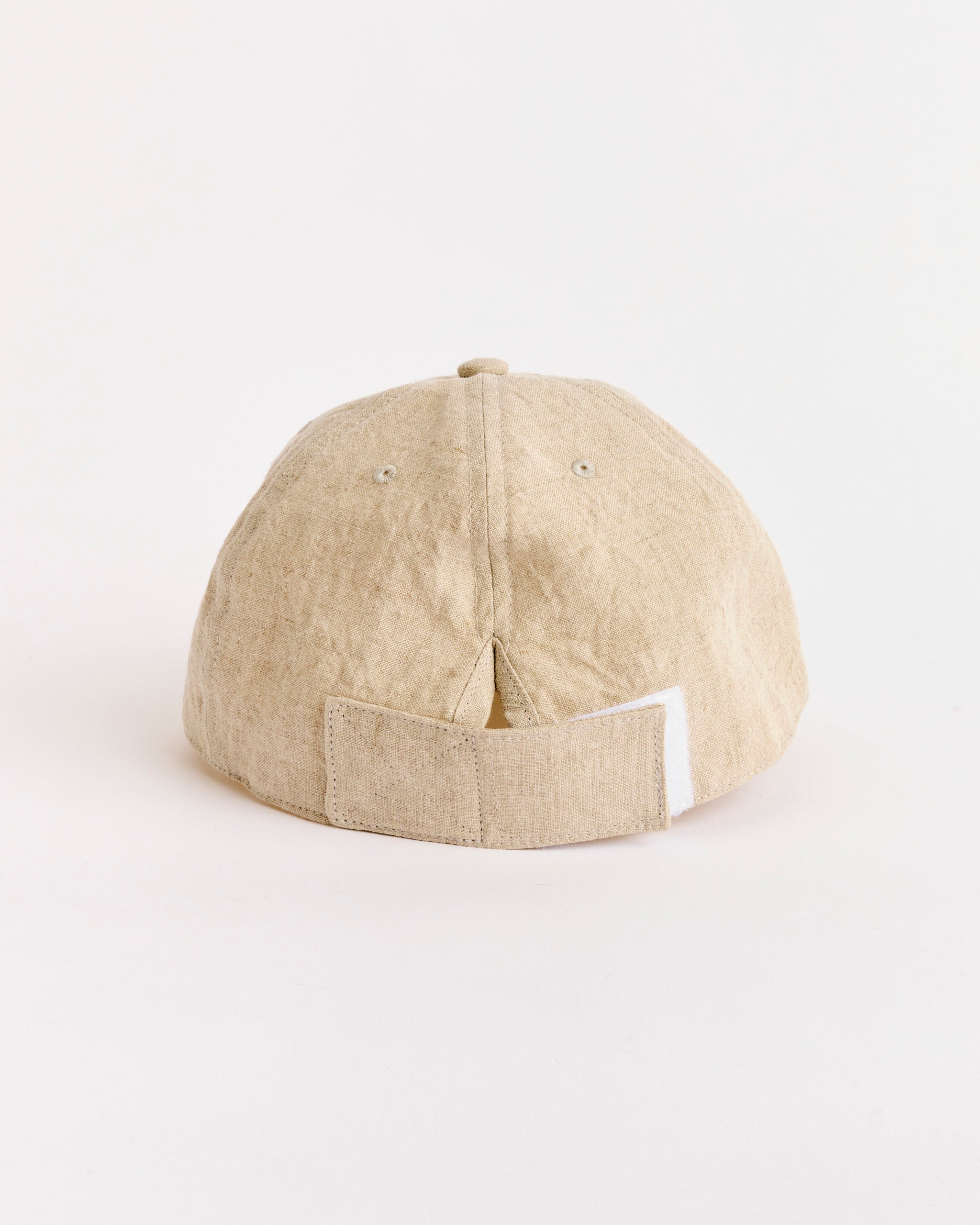 The SMOCK Velcro Back Cap in Sun Dried Linen Ivory is shown from the back, featuring an adjustable velcro strap and a small opening above it, set against a plain white background.