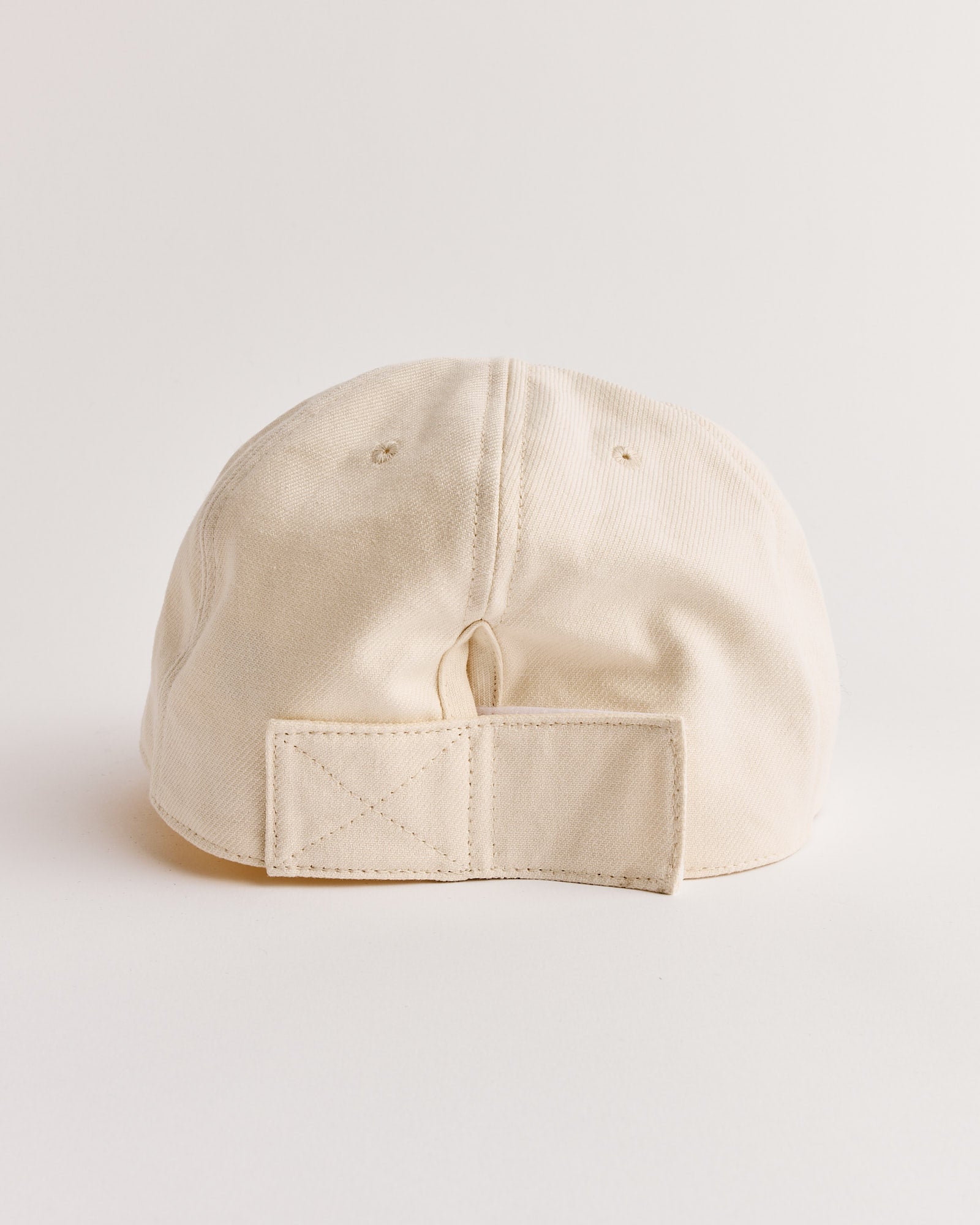 The SMOCK Velcro Back Cap in French Cotton Twill Cream is shown from the back, featuring a 6-panel design, adjustable fabric strap with rectangular patch, and crafted from Japanese-woven cotton, set against a plain white background.