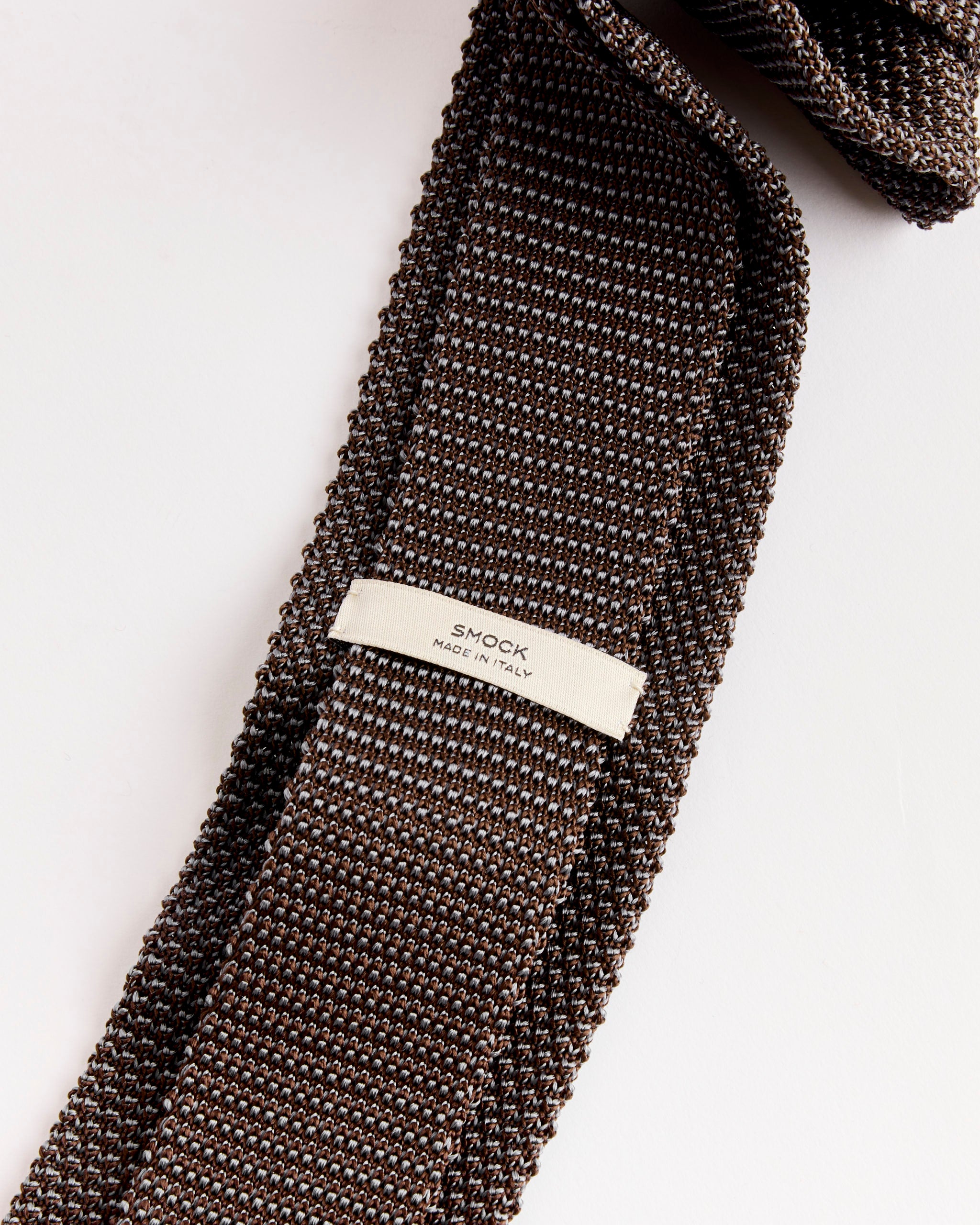 A close-up of the SMOCK Silk Knit Tie in Brown/Lavender shows its circular knit and a white "SMOCK MADE IN ITALY" label, all set against a white background.